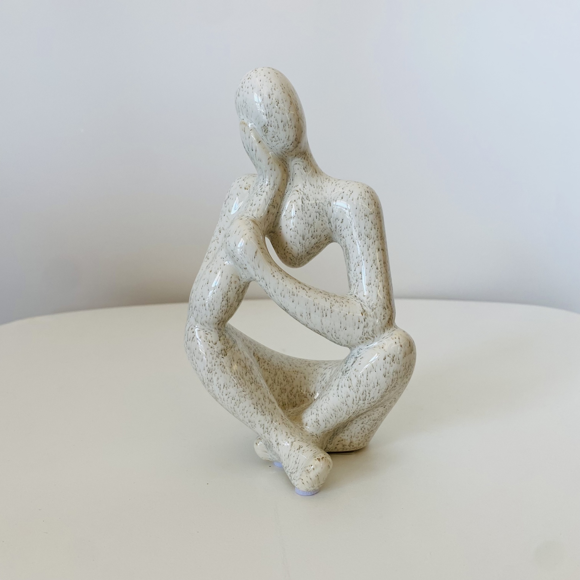 Figura decorativa abstrata sentada em tom bege claro com textura pontilhada