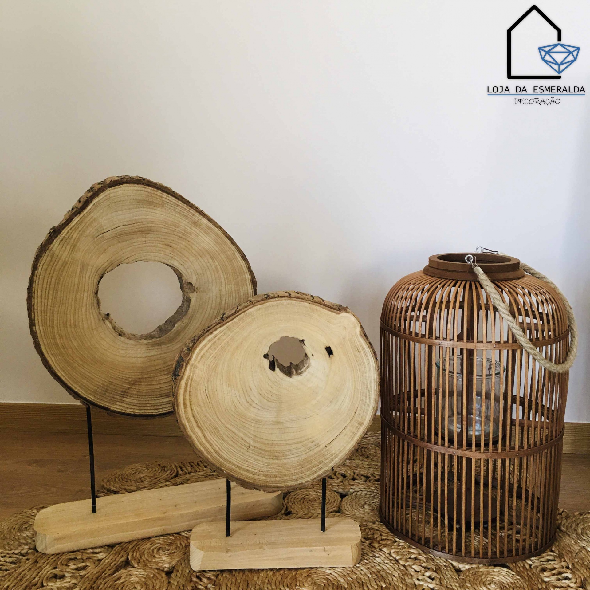 Decoração com dois troncos de madeira natural e candeeiro de vidro com estrutura em vime castanho