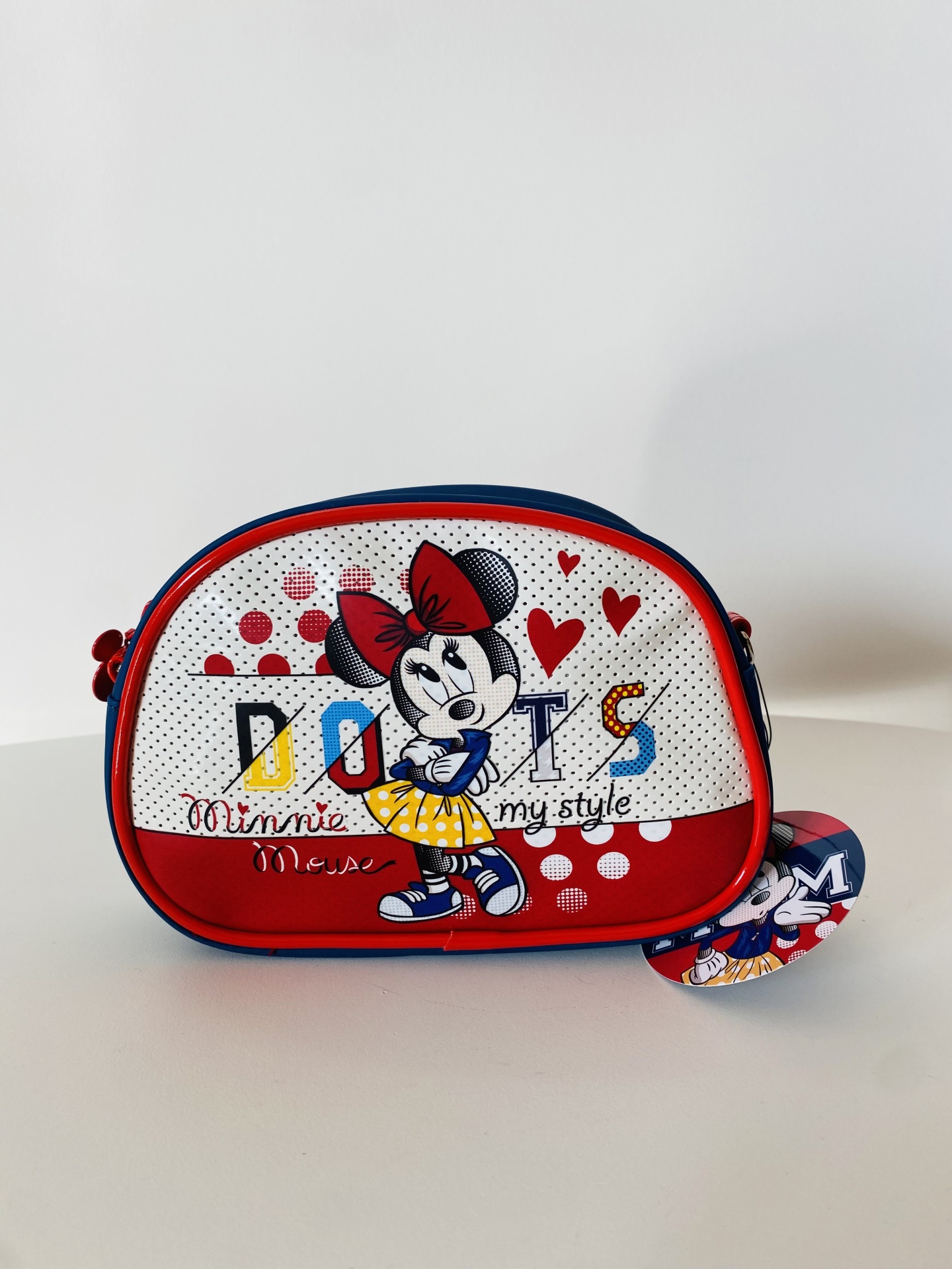 Bolsa infantil pequena branca com estampa da Minnie Mouse e detalhes vermelhos e azuis.