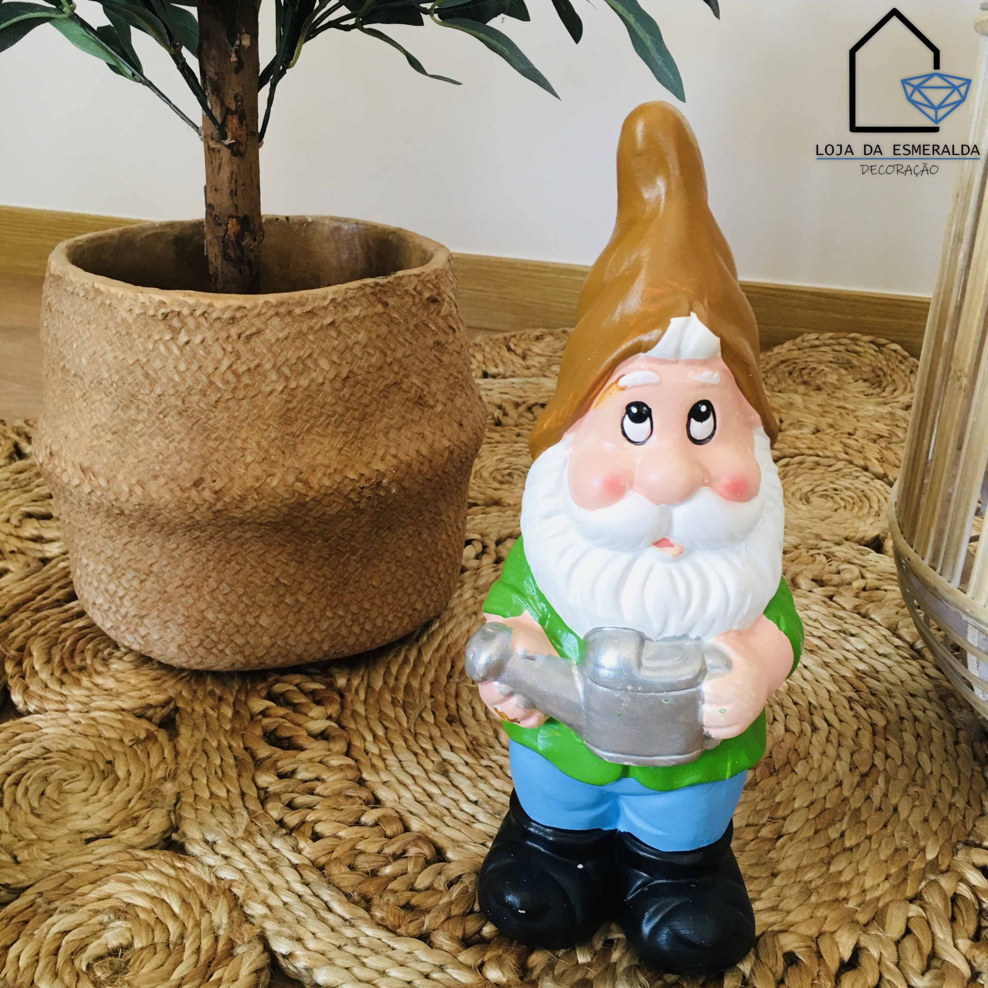 Gnomo decorativo com chapéu castanho e roupas coloridas ao lado de vaso de tecido