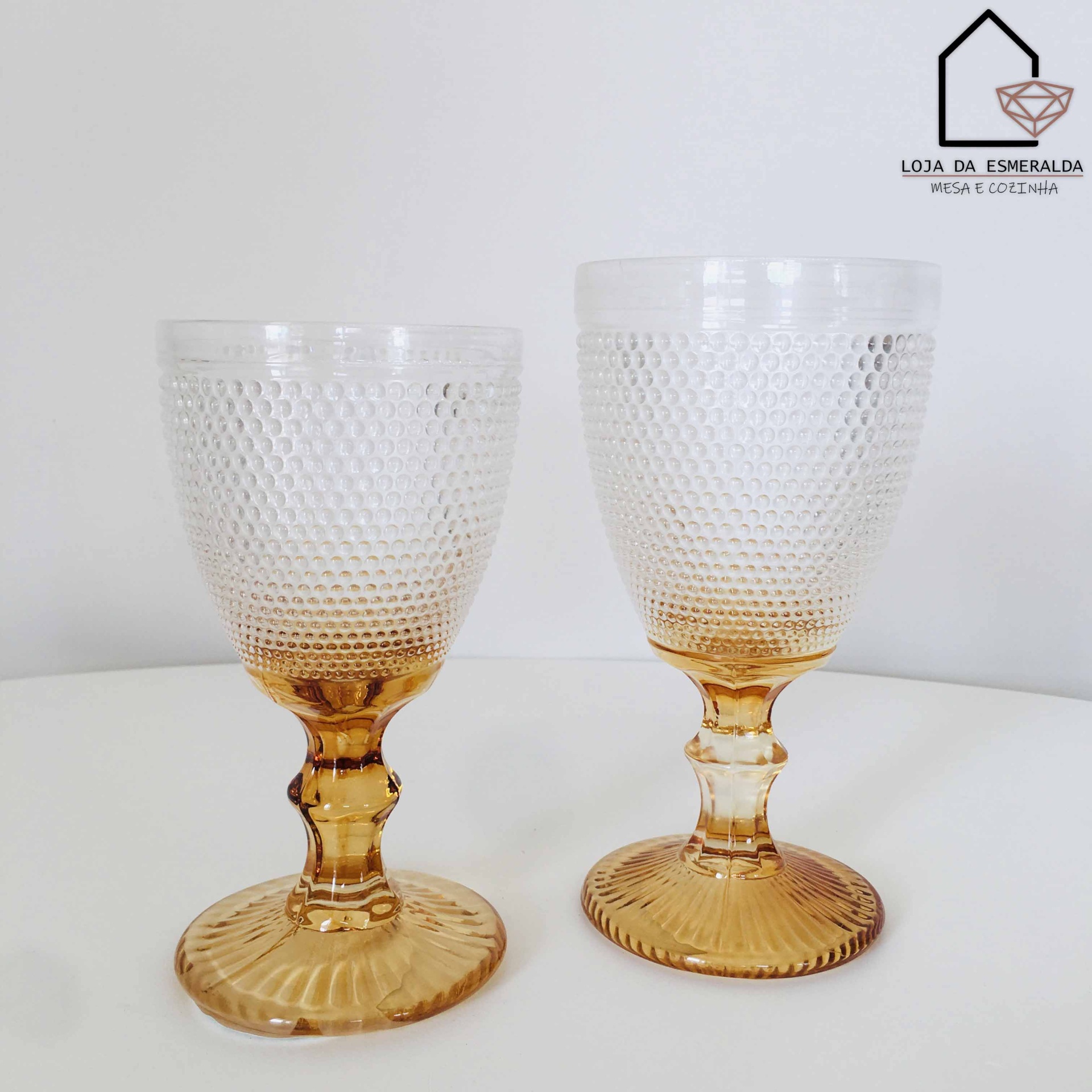 Dois copos de vidro texturizados com base âmbar sobre superfície branca