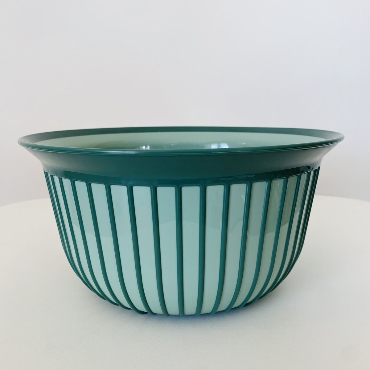Tigela verde com riscas verticais numa superfície branca