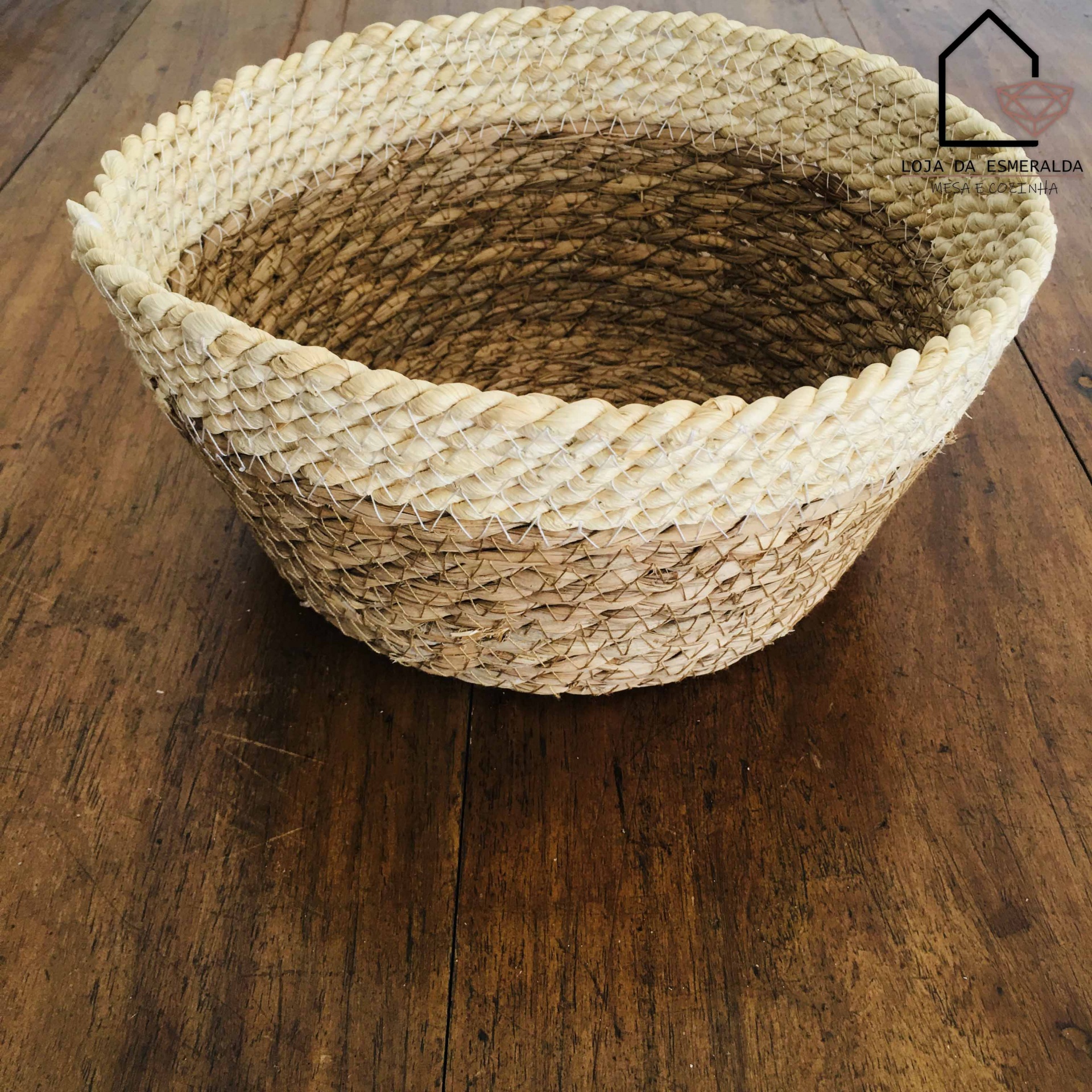 Cesto redondo em fibras naturais sobre mesa de madeira