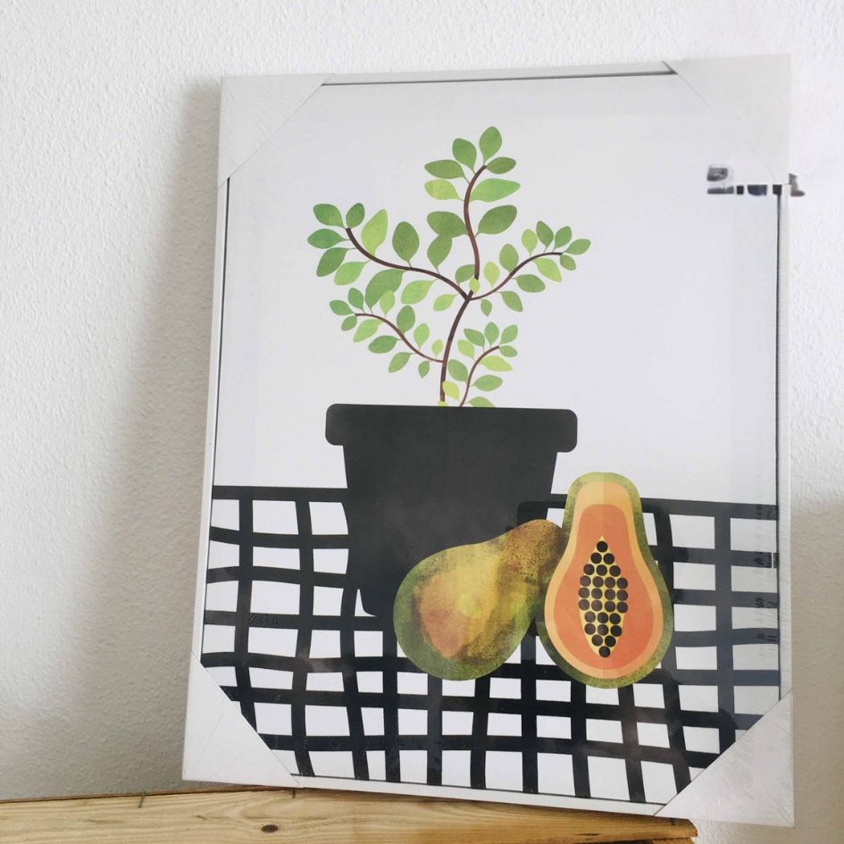 Quadro decorativo com desenho de planta em vaso e frutas em superfície xadrez