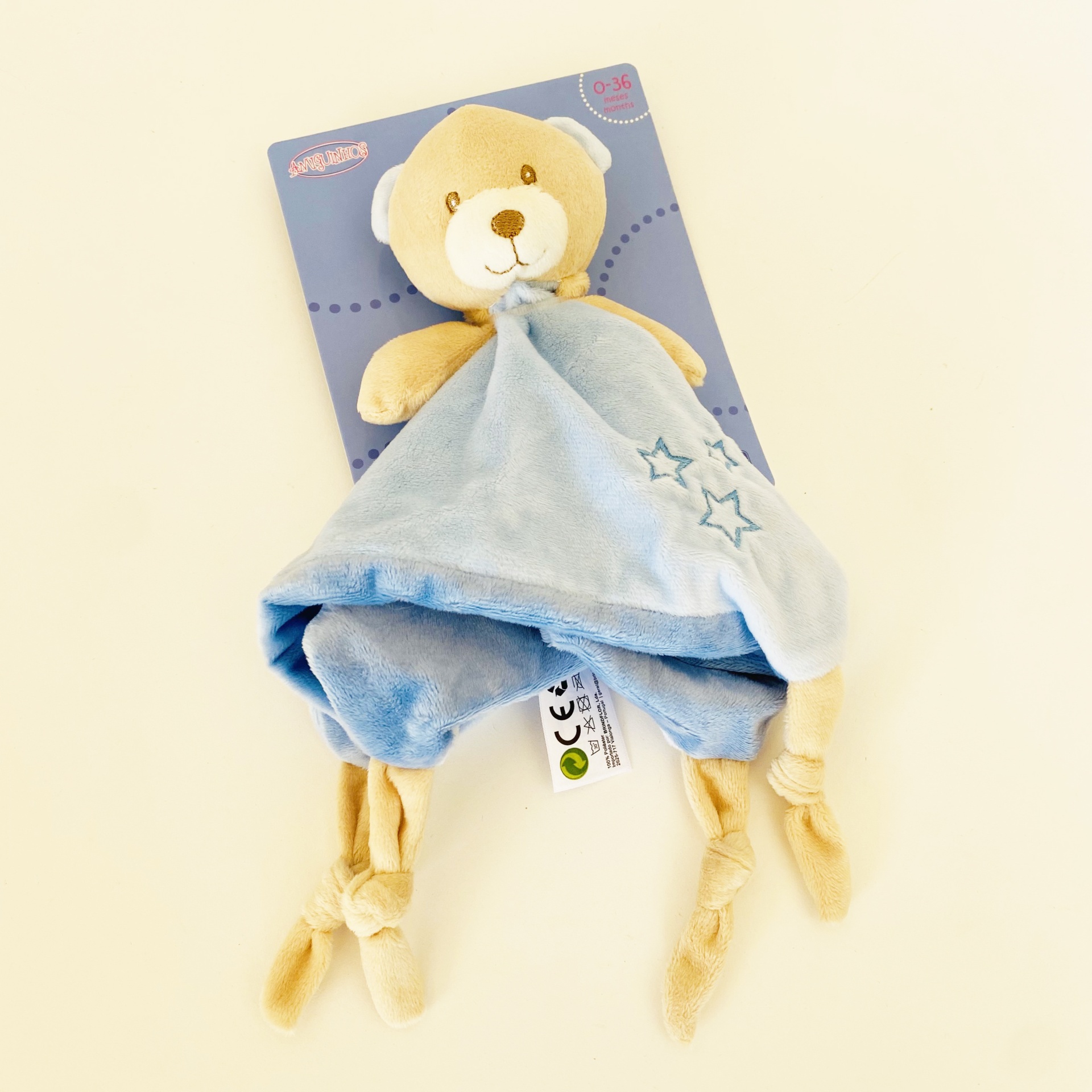 Pelúcia de ursinho com manta azul e cartão de embalagem azul