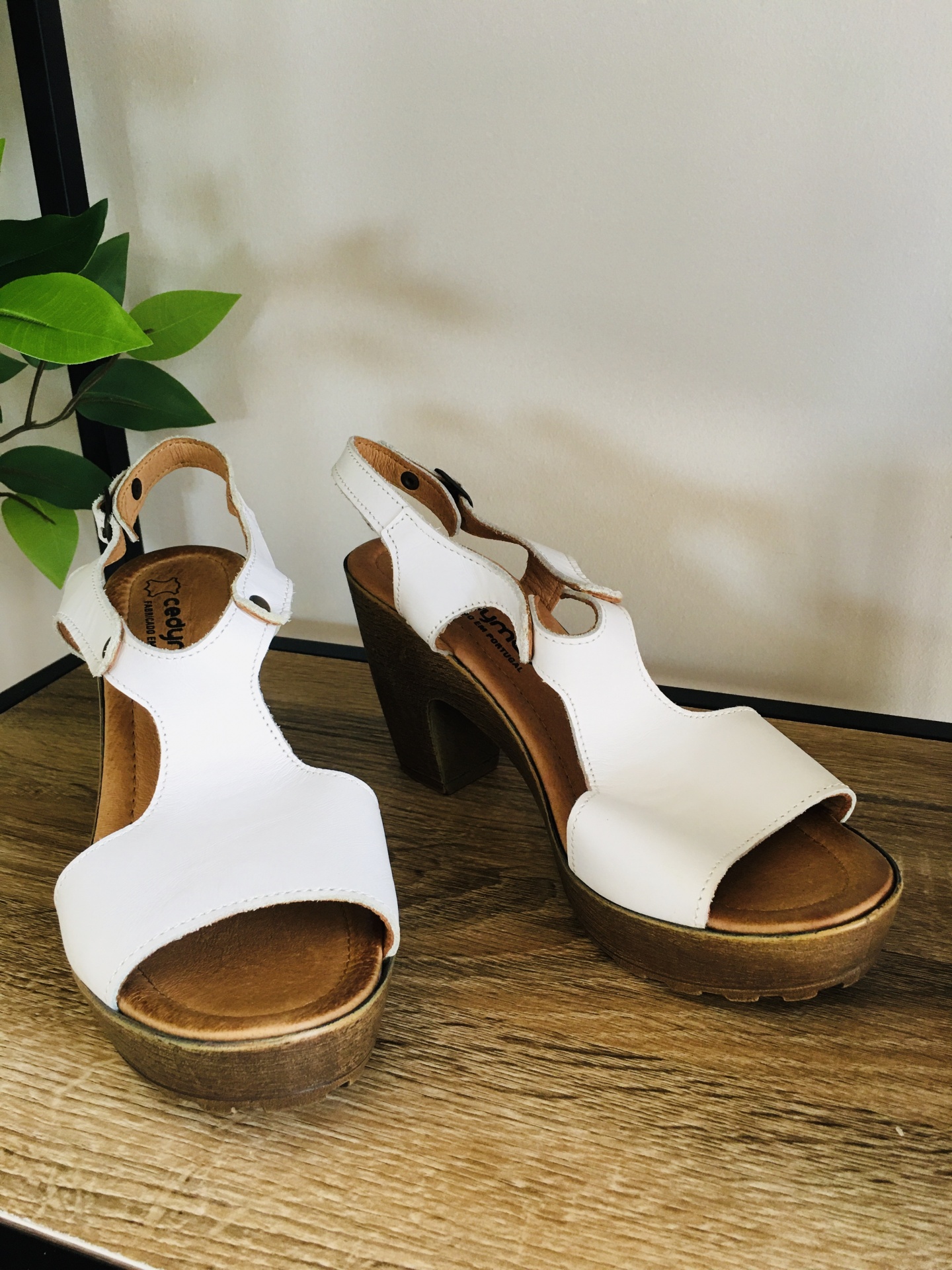 Sapatos de salto alto branco com sola de madeira sobre mesa de madeira