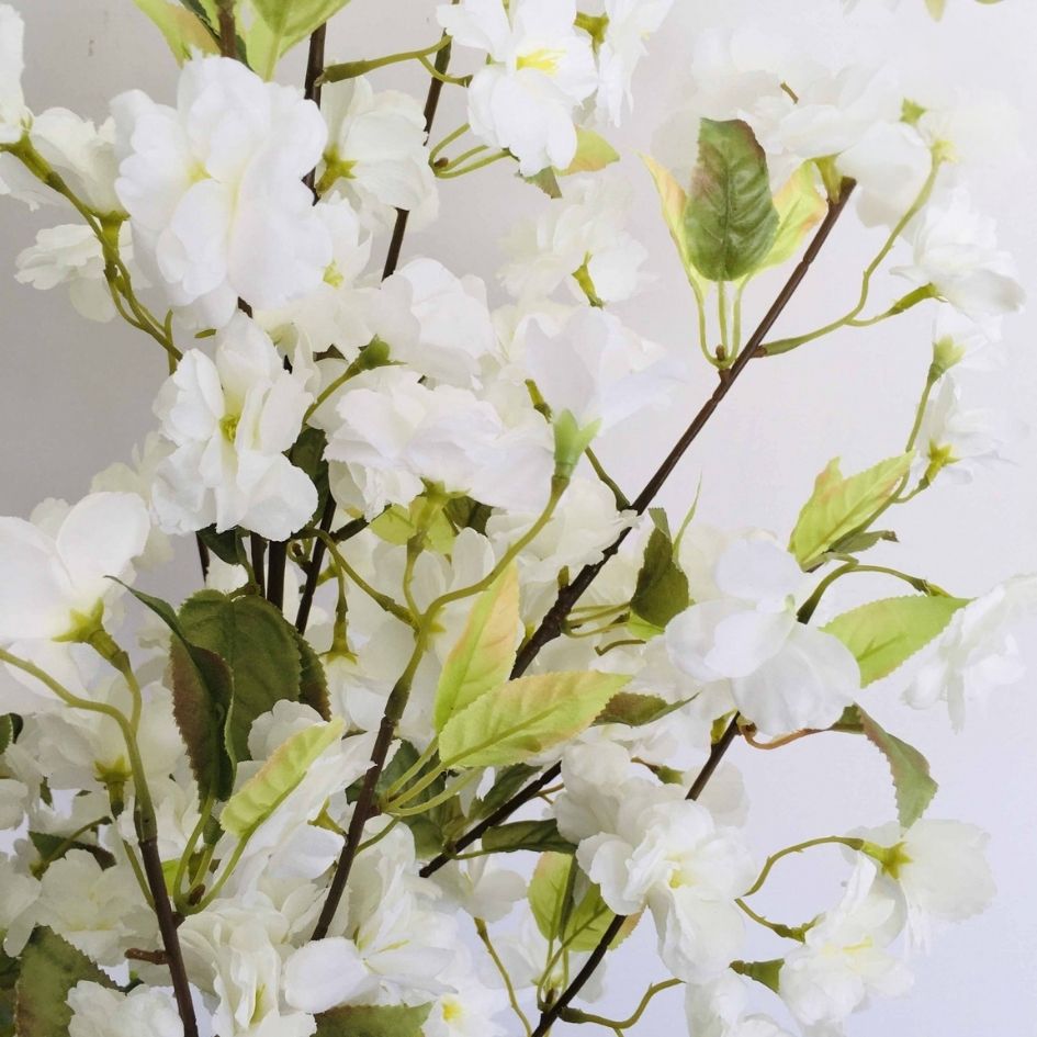 Ramo de flores artificiais brancas com folhas verdes e caules castanhos