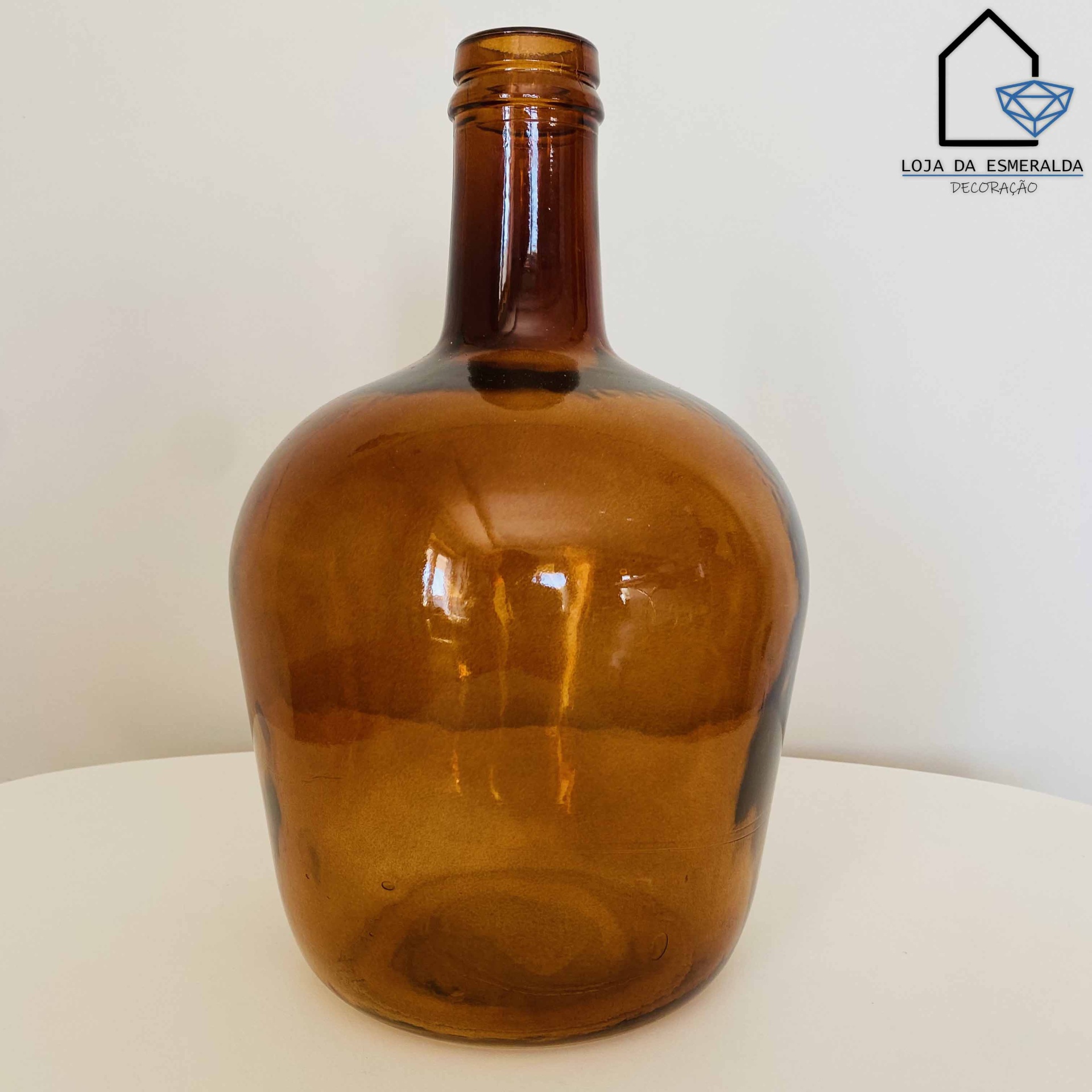 Garrafa de vidro âmbar arredondada com logotipo da loja ao fundo