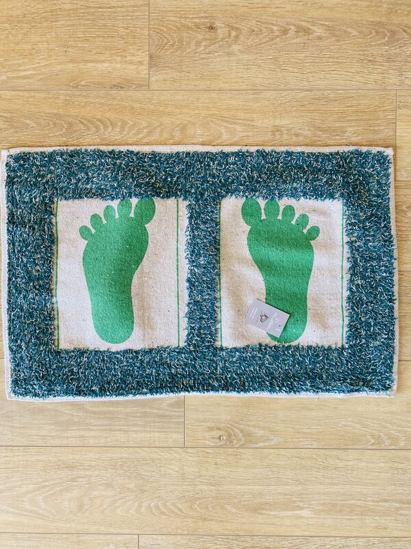 Tapete com pegadas verdes e textura felpuda azul