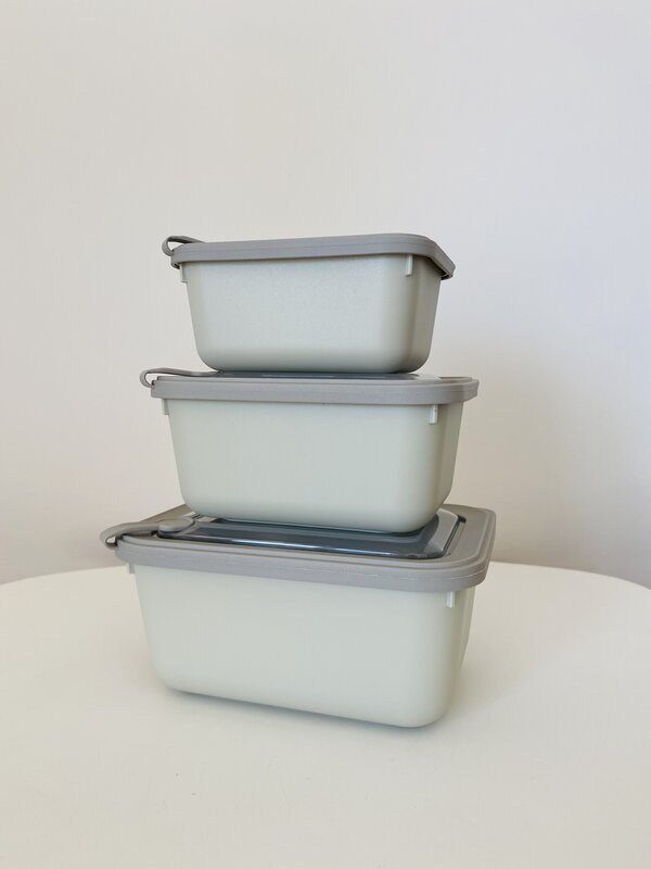 Três caixas herméticas de plástico cinzento e branco empilhadas