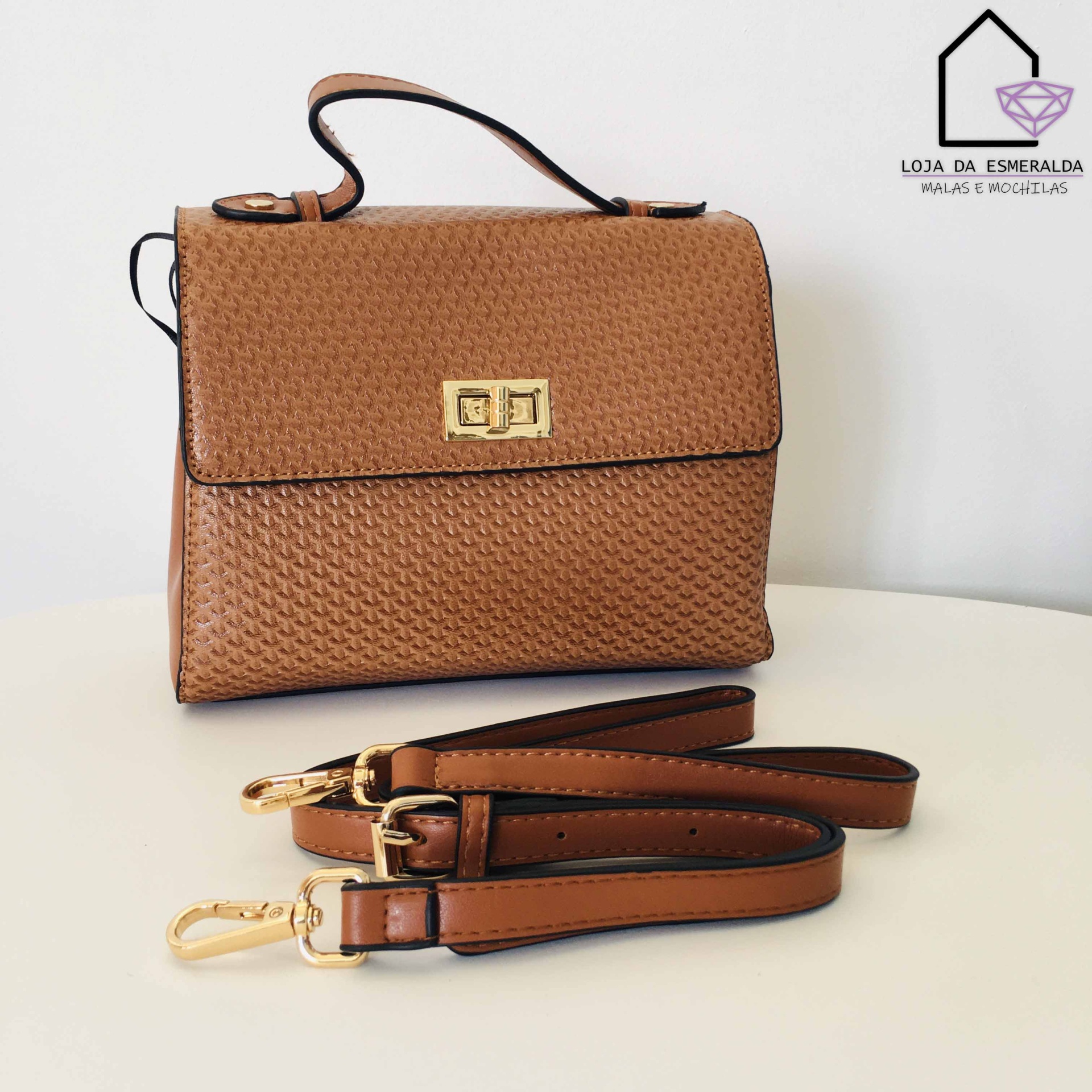 Mala castanha texturizada com fecho dourado e duas alças sobre mesa branca