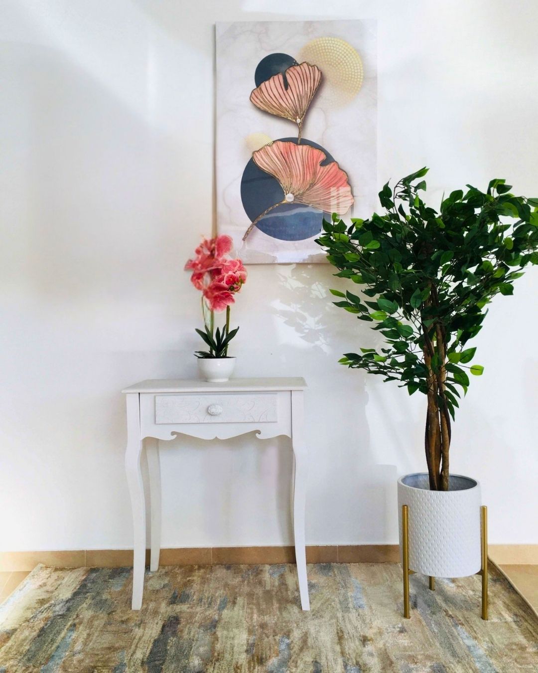 Mesa branca de madeira com uma gaveta decorada e plantas decorativas sobre tapete em tons terra