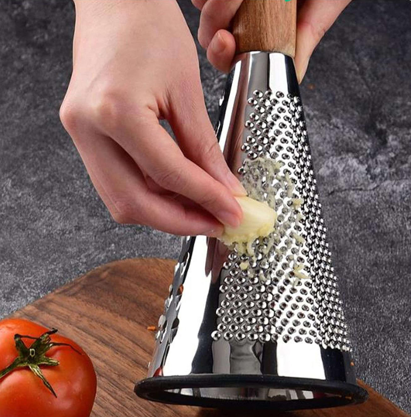 Ralador metálico com cabo de madeira sendo usado para ralar alho, com tomate ao lado