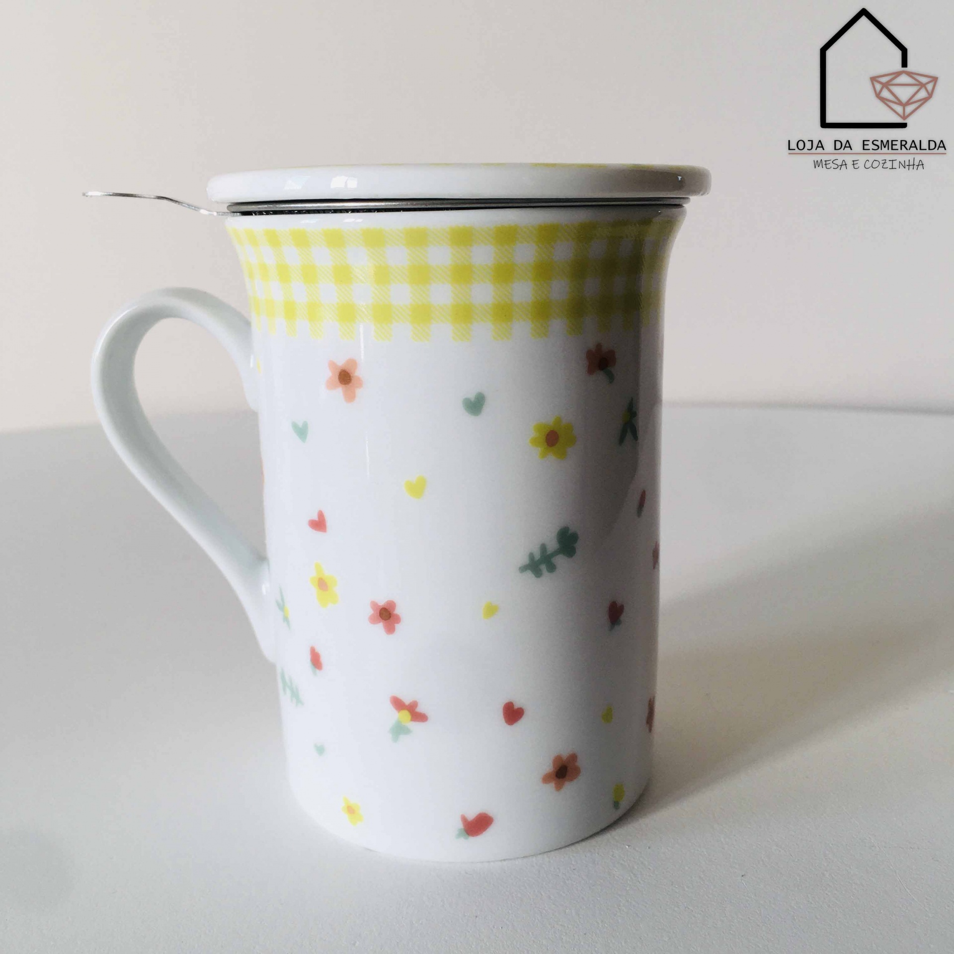 Caneca branca com flores coloridas, tampa e colher em superfície branca