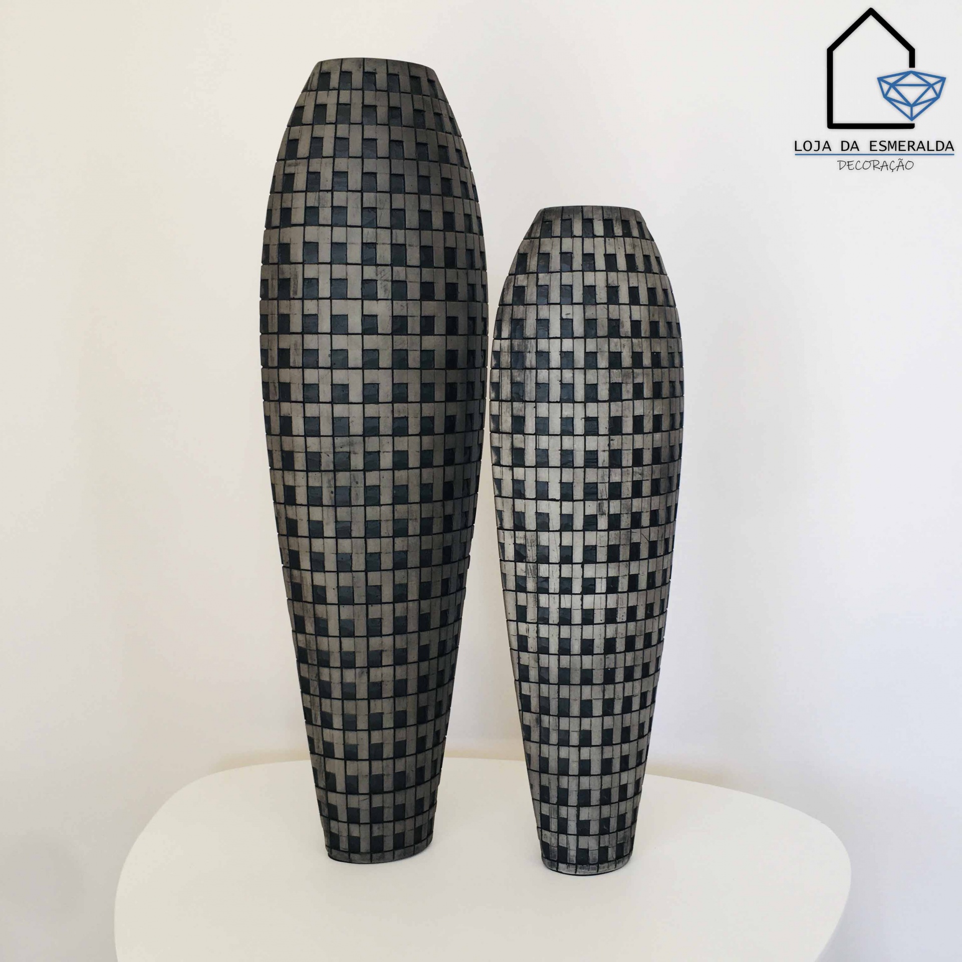 Esculturas decorativas preto e cinza com padrão quadriculado sobre mesa branca