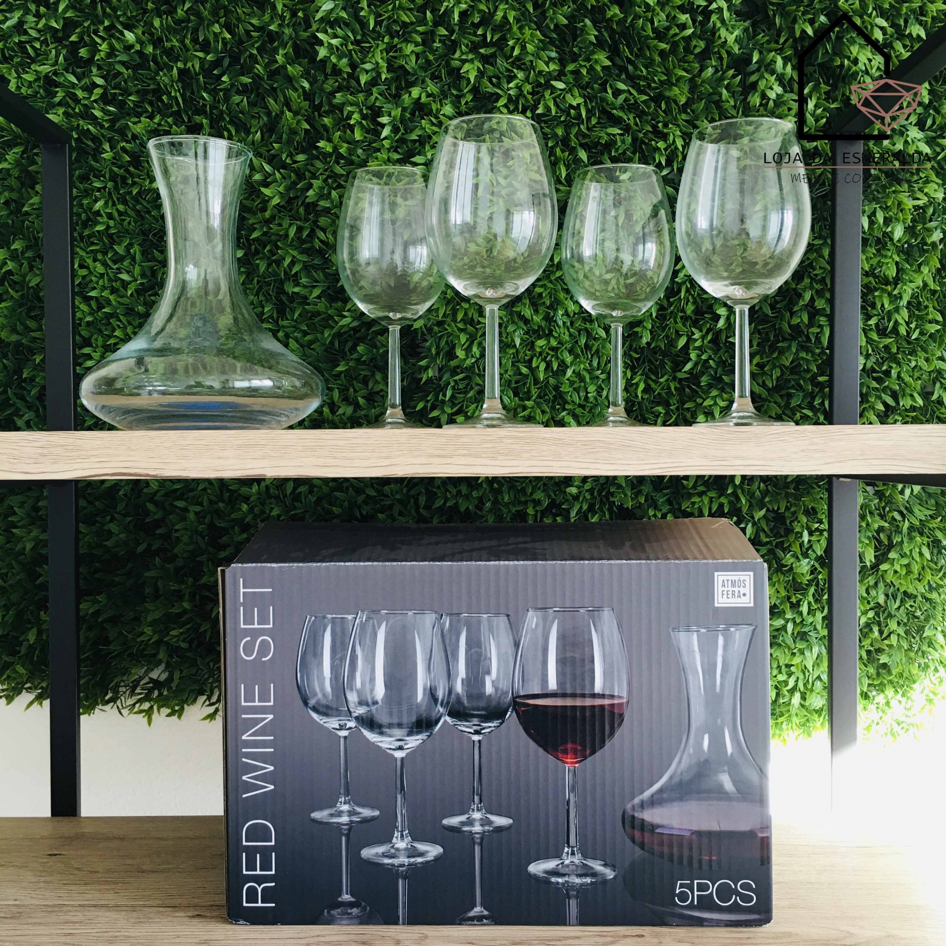 Conjunto de vinho tinto com copos e decantador em vidro transparente numa estante de madeira com fundo verde