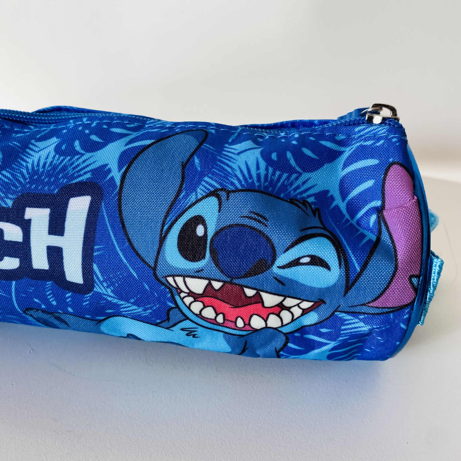 Estojo azul com imagem do personagem Stitch e padrão de folhas tropicais