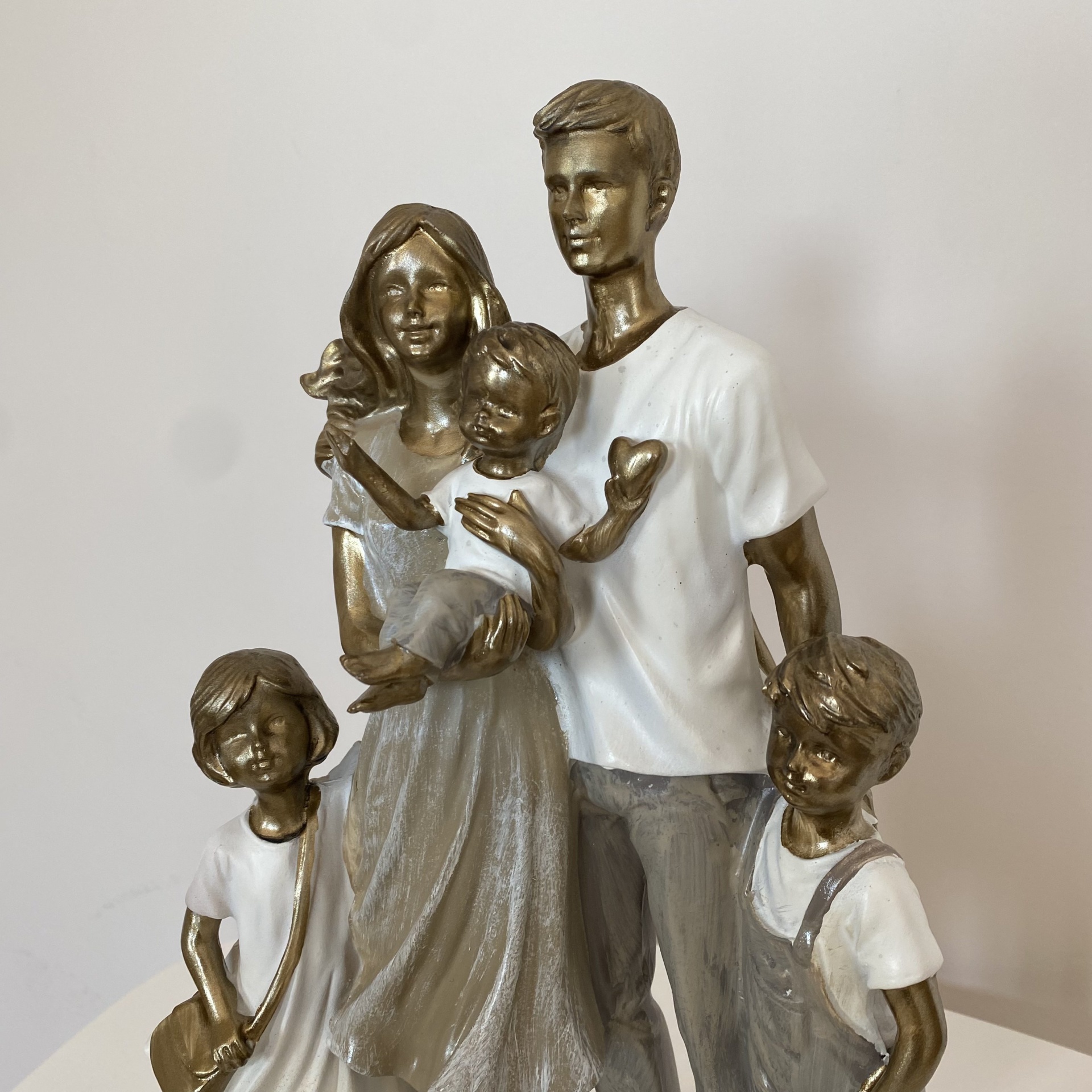 Estátua decorativa de família com cinco pessoas em resina ou cerâmica, em tons de bronze e branco.