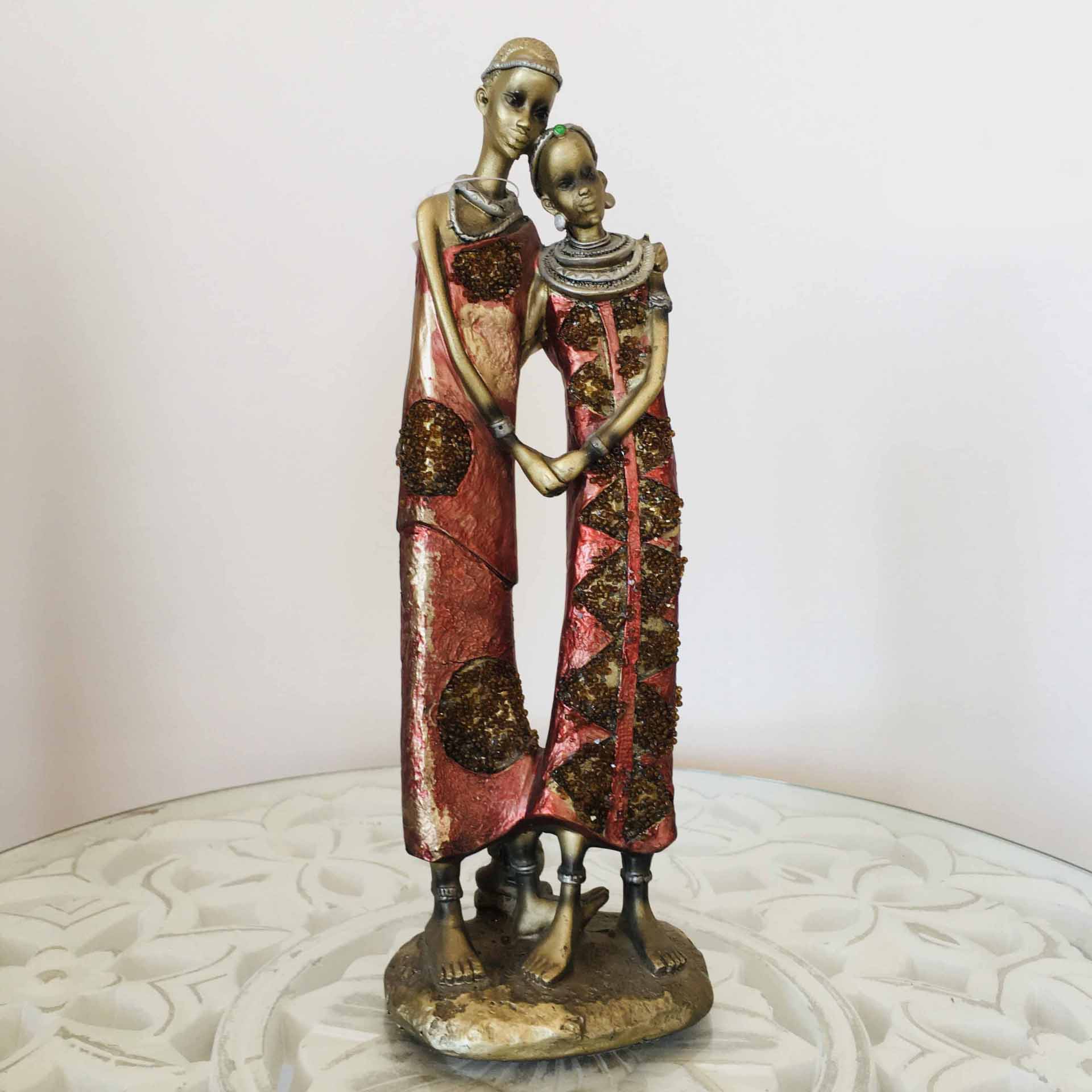Estátua decorativa de duas figuras femininas com vestidos vermelhos e detalhes dourados