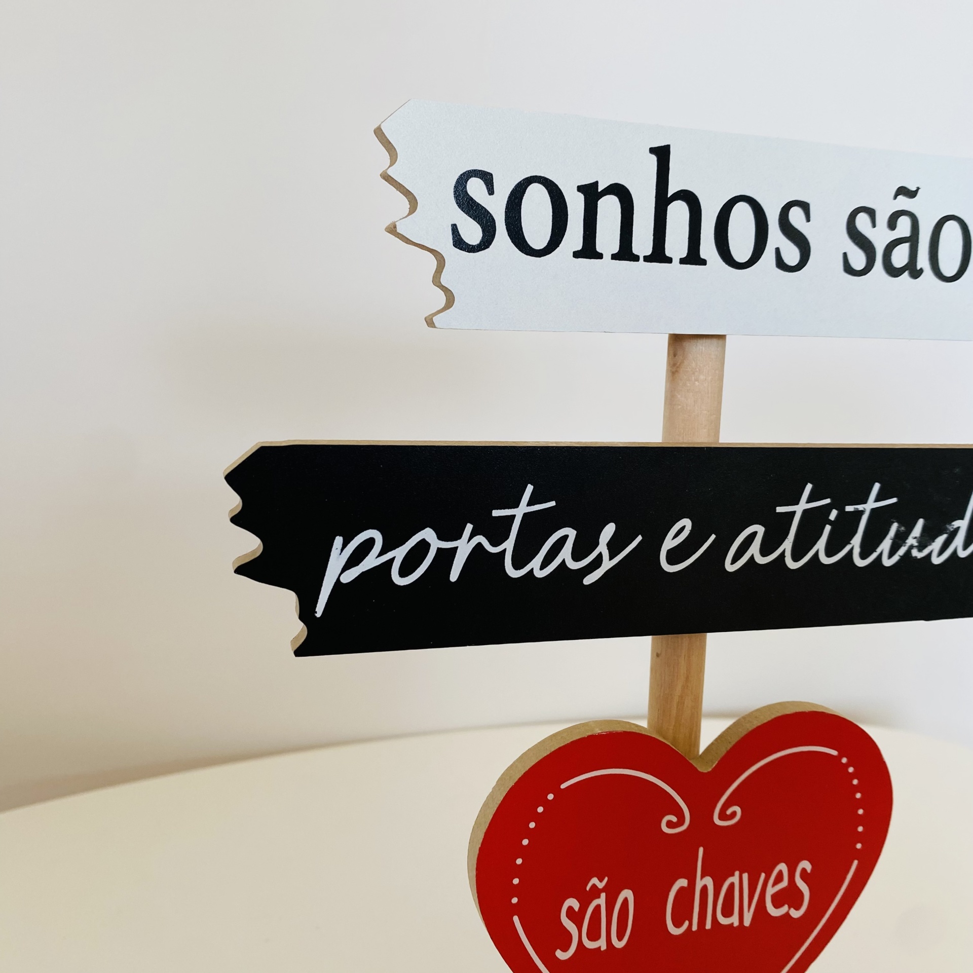 Placa decorativa de madeira com textos em português e formato de coração vermelho.