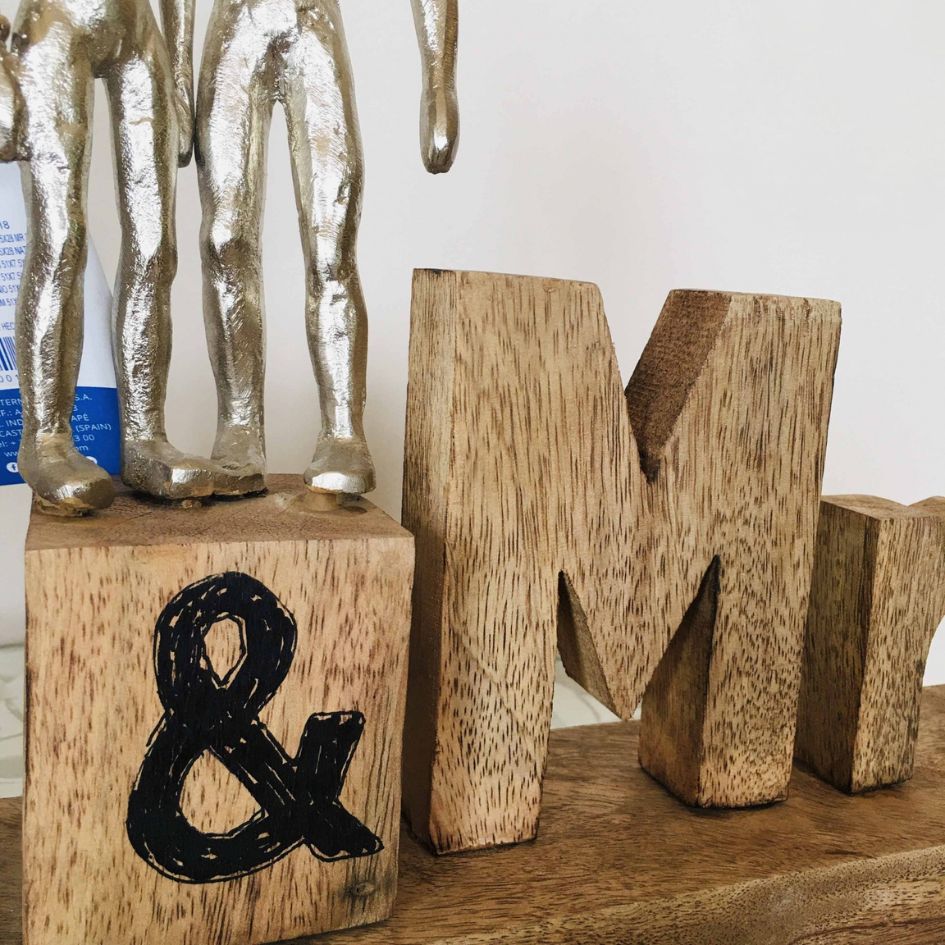 Escultura decorativa com figuras humanas em metal sobre base de madeira e letras de madeira