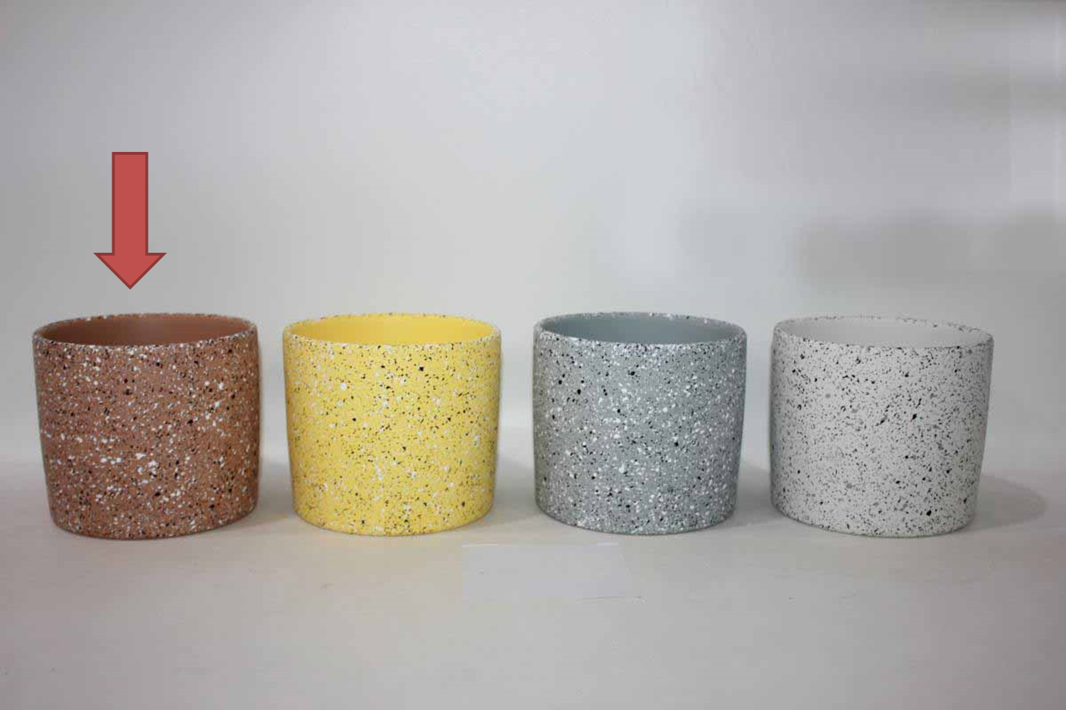 Quatro vasos cilíndricos salpicados em castanho, amarelo, cinzento e branco