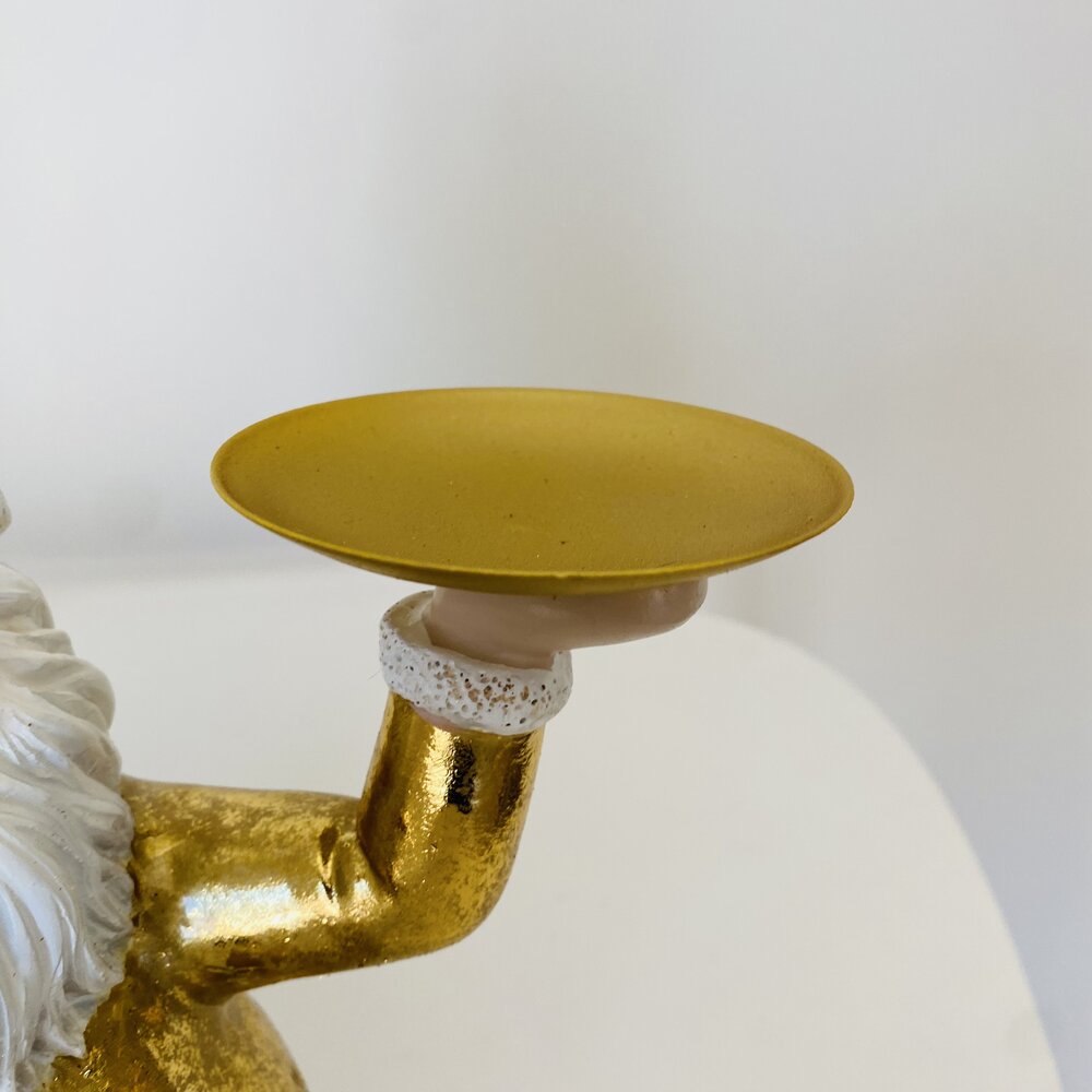 Braço dourado segurando prato amarelo fosco com pulseira branca com dourado