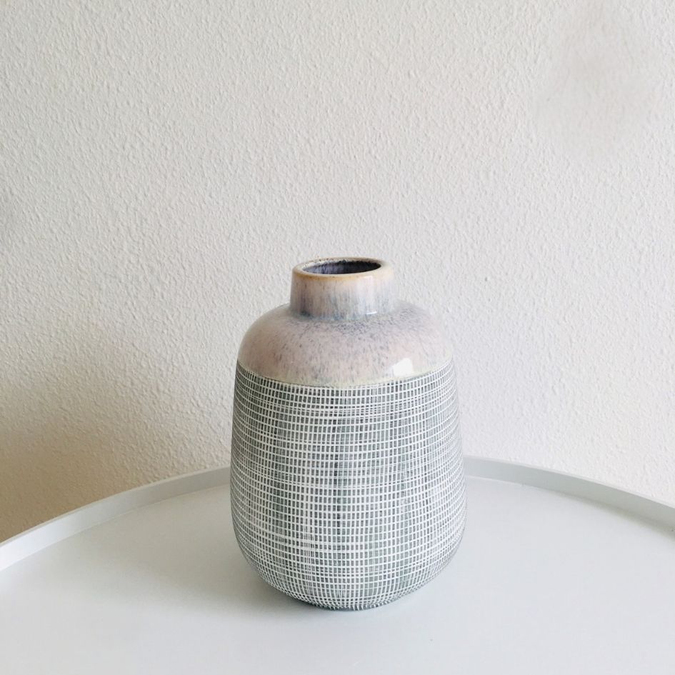 Vaso de cerâmica cinza e branco com padrão quadriculado em mesa branca