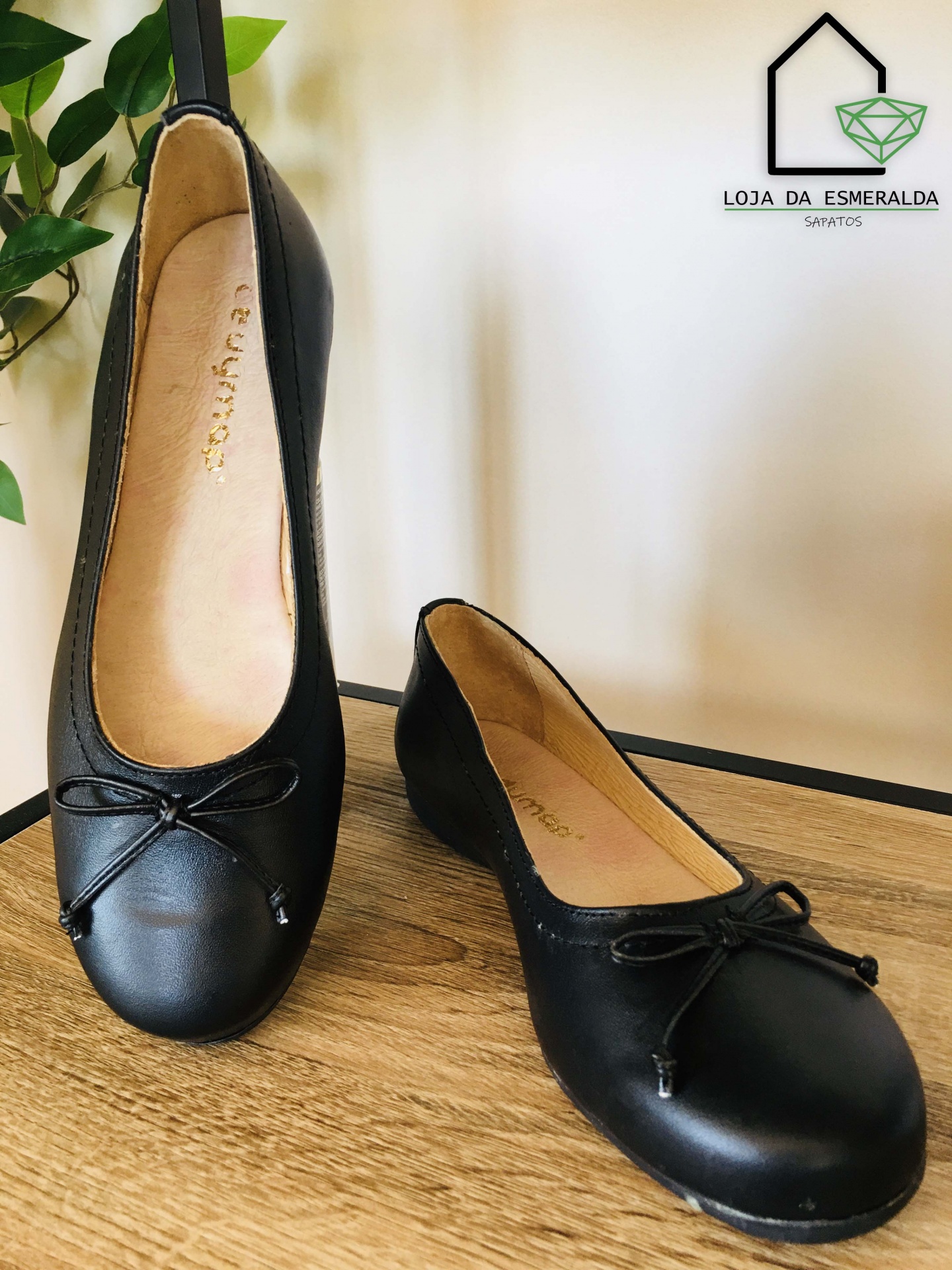 Sapatilhas pretas com laço numa superfície de madeira