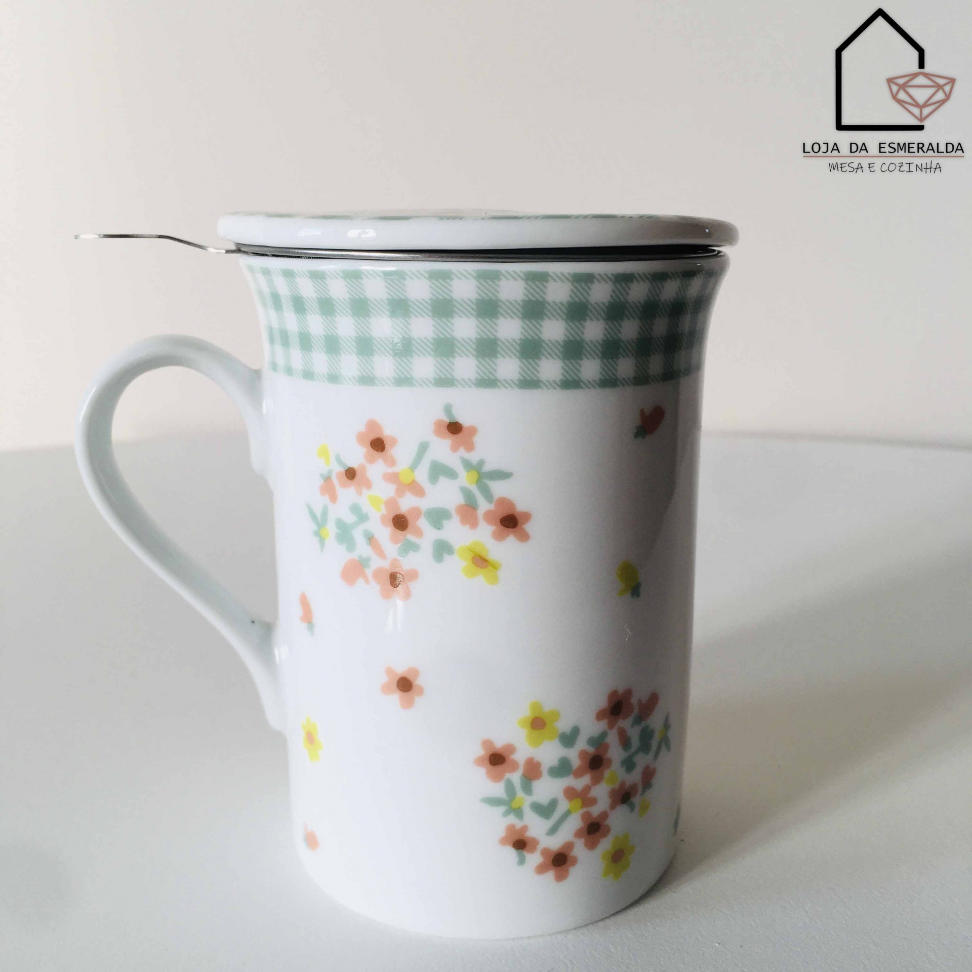 Caneca branca com flores coloridas, tampa de vidro e colher metálica