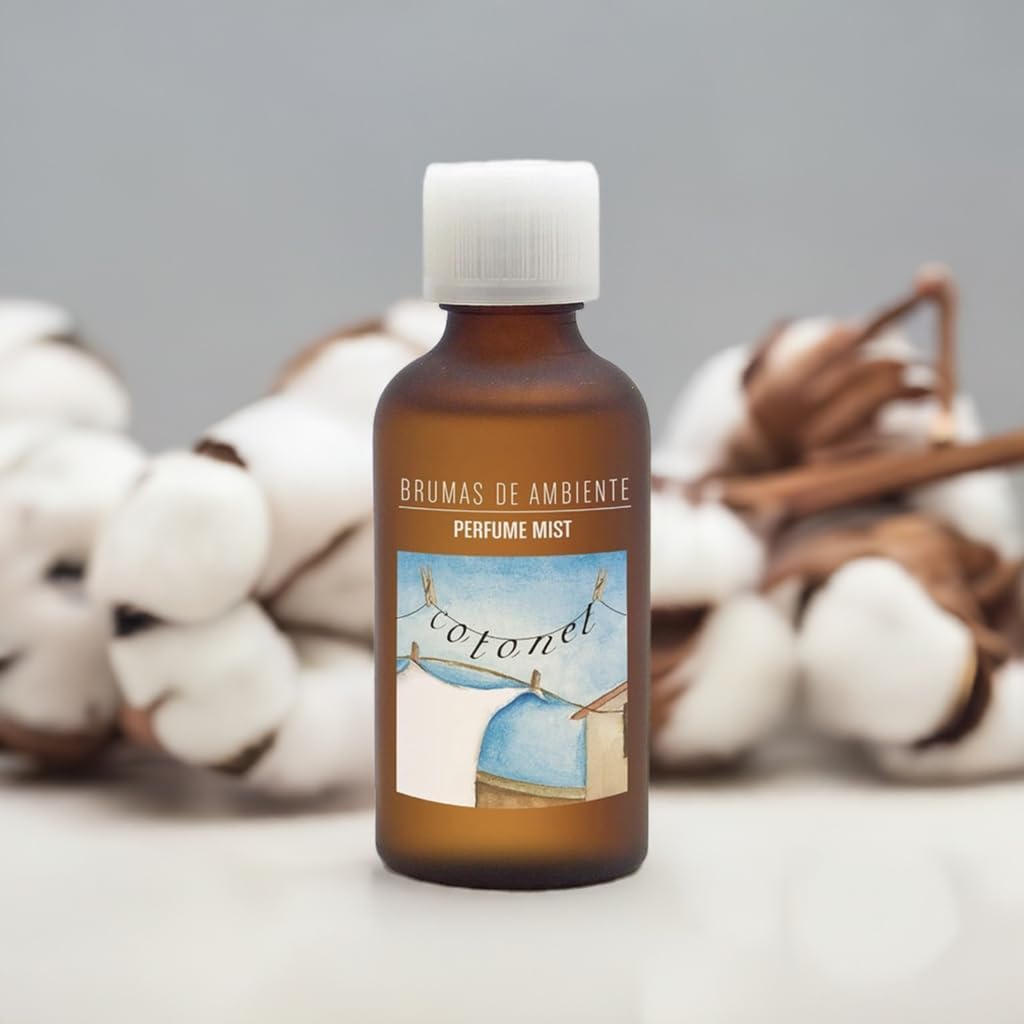 Frasco de brumas de ambiente com etiqueta azul e branca em fundo claro com algodão.