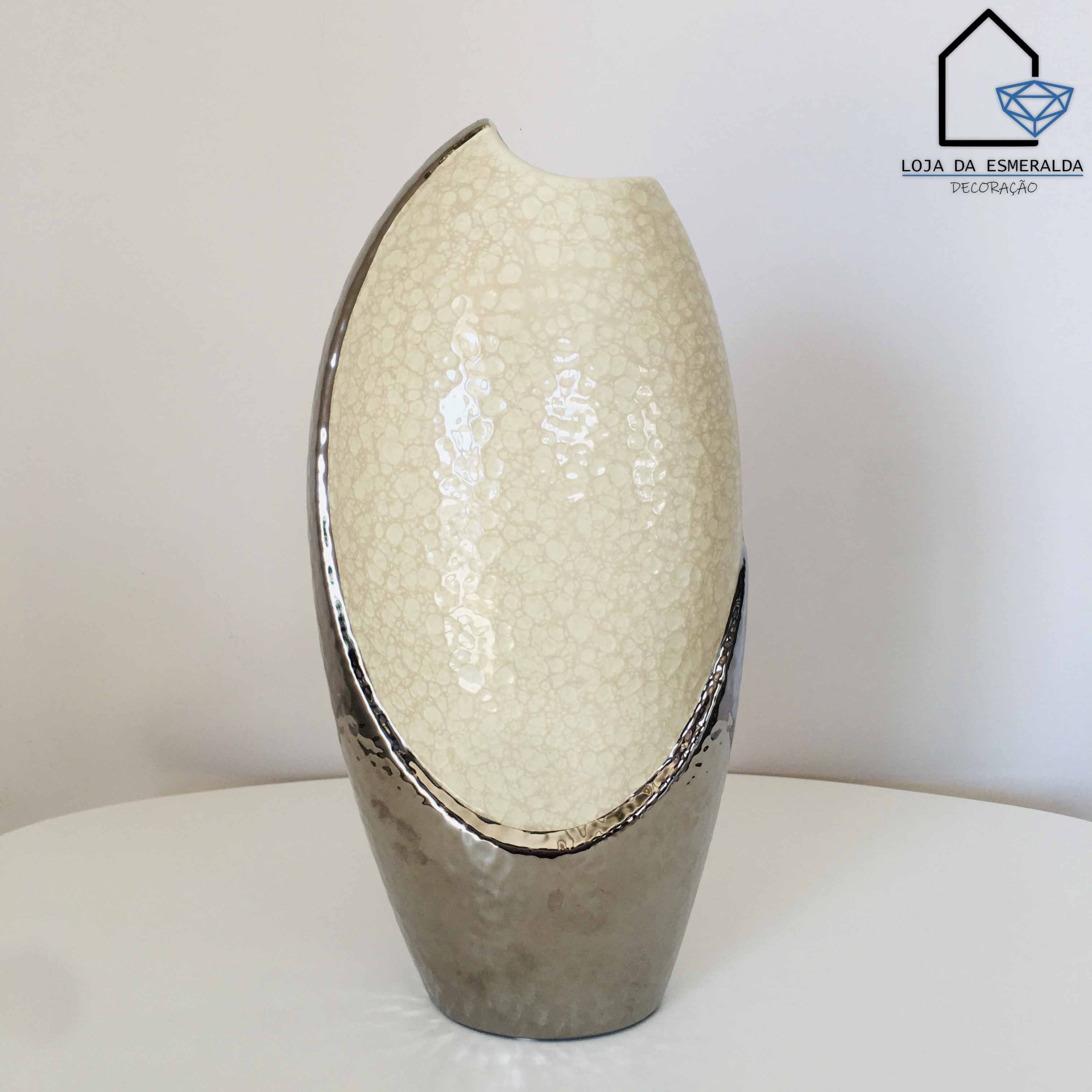 Vaso decorativo creme com base metálica prateada em superfície branca