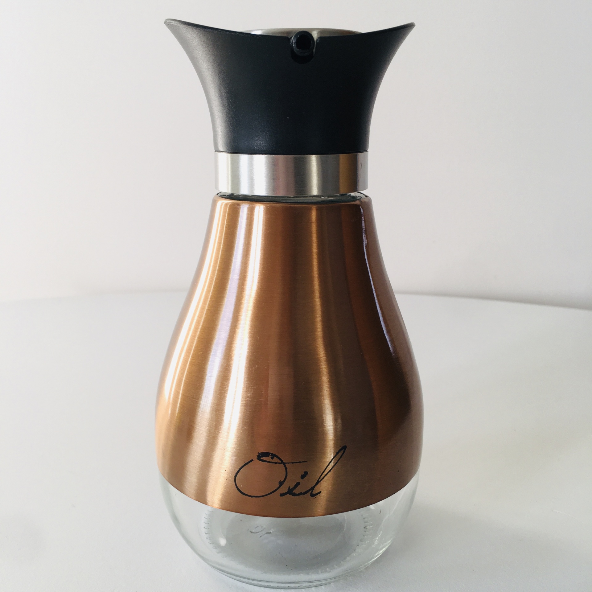 Garrafa doseadora para óleo com corpo em vidro e parte superior dourada, tampa preta