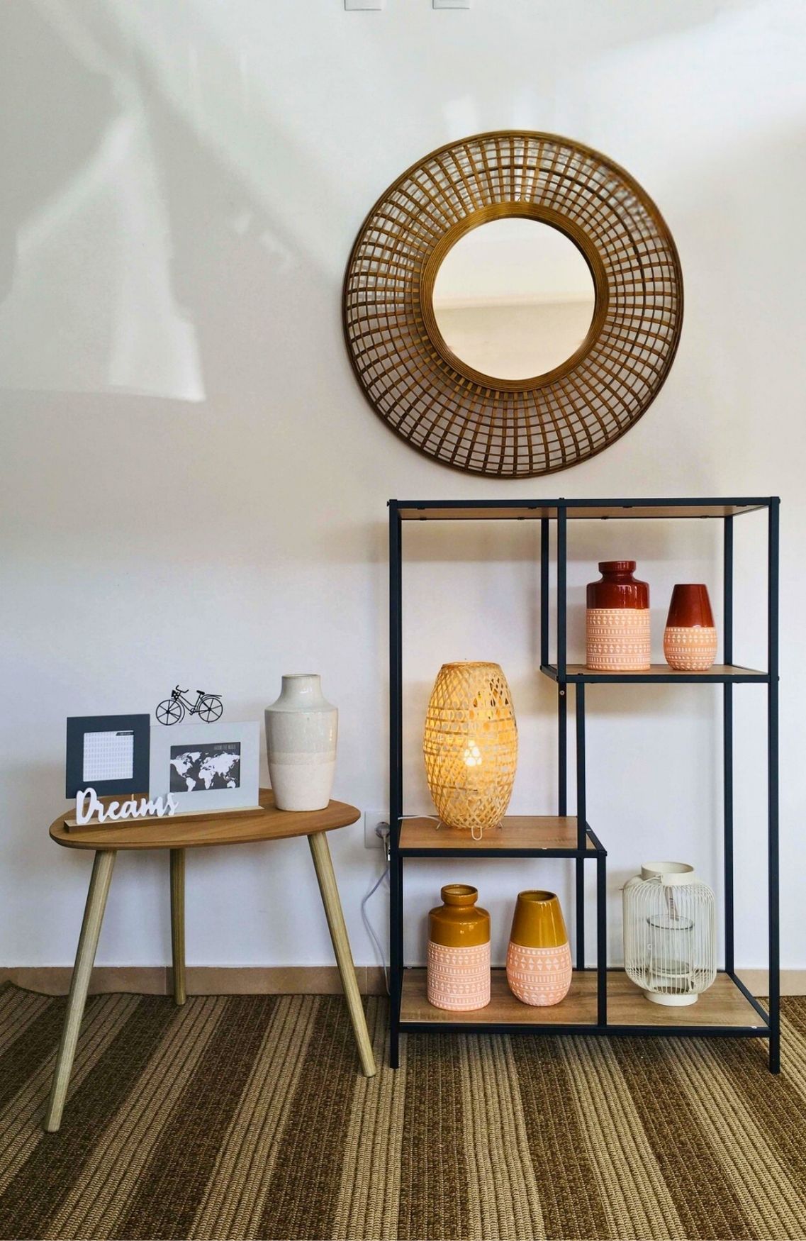 Espelho redondo dourado, estante preta com vasos decorativos, mesa de madeira com decoração Dreams