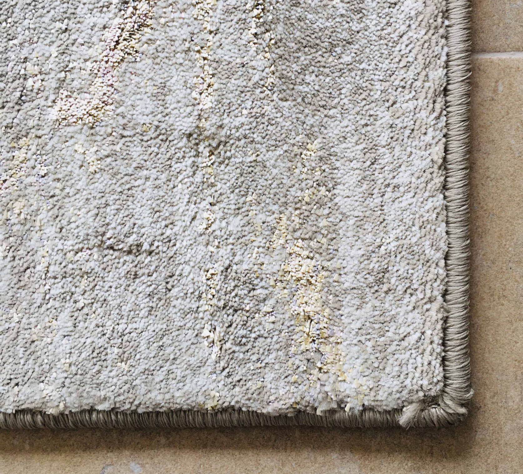 Tapete cinza claro com textura felpuda e bordas arredondadas sobre pavimento de azulejos bege