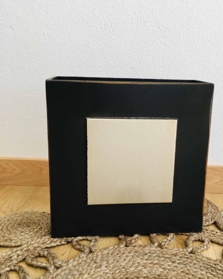 Vaso cerâmico quadrado preto com detalhe creme, sobre tapete rústico e chão de madeira