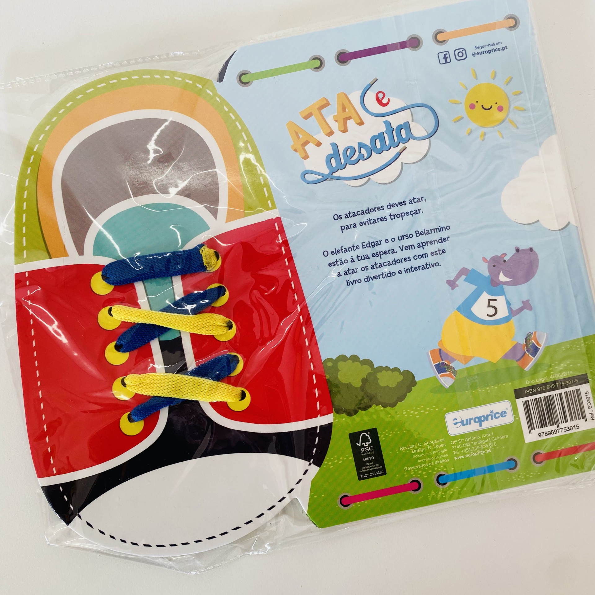 Livro infantil de tecido formato sapato colorido com cadarços e título 'ATA e desata'