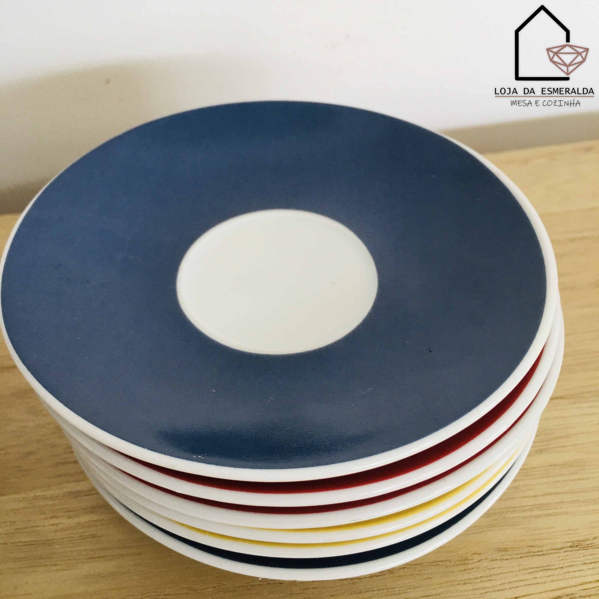 Pratos coloridos empilhados com círculo branco central sobre mesa de madeira