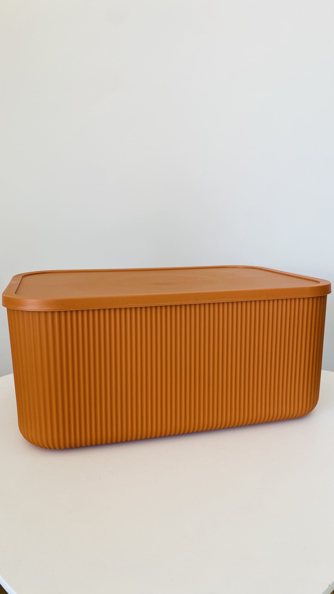 Caixa de plástico castanho alaranjado com tampa e textura vertical