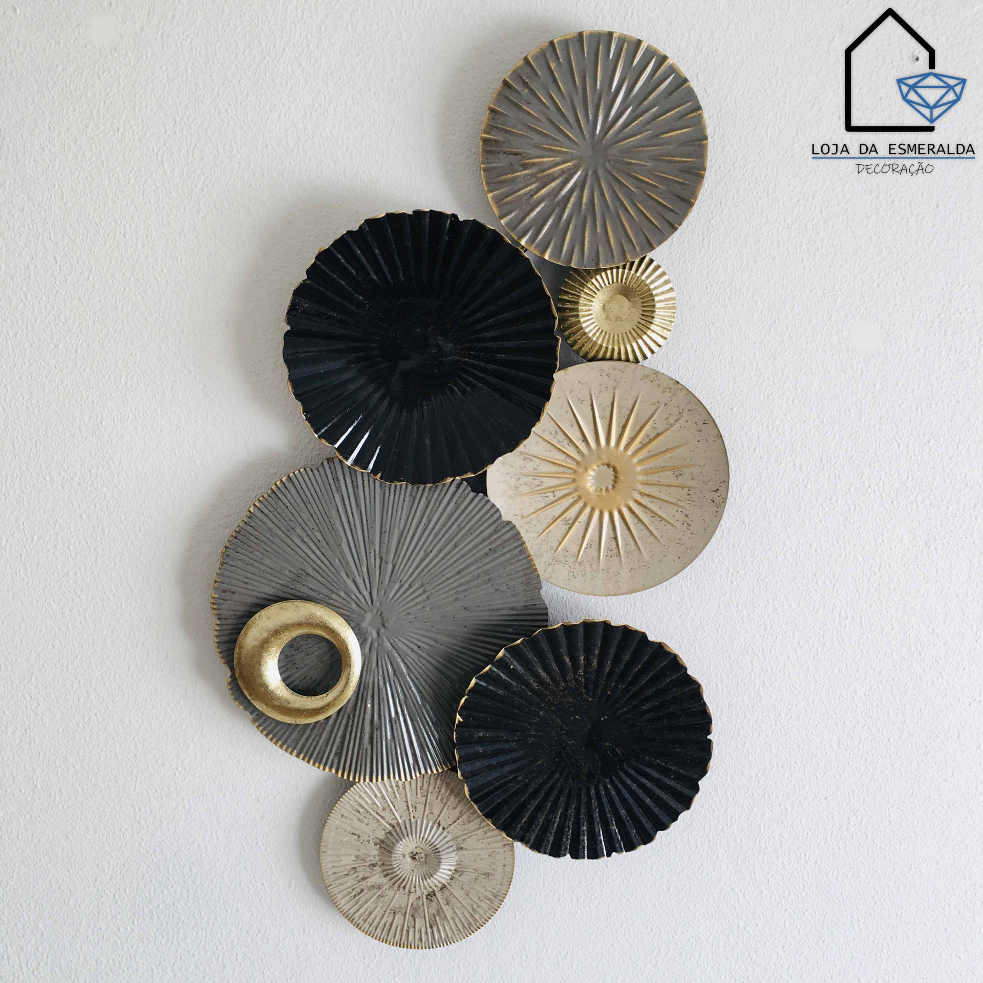 Painel decorativo de parede com círculos texturizados em cinza, preto, bege e dourado sobre parede branca