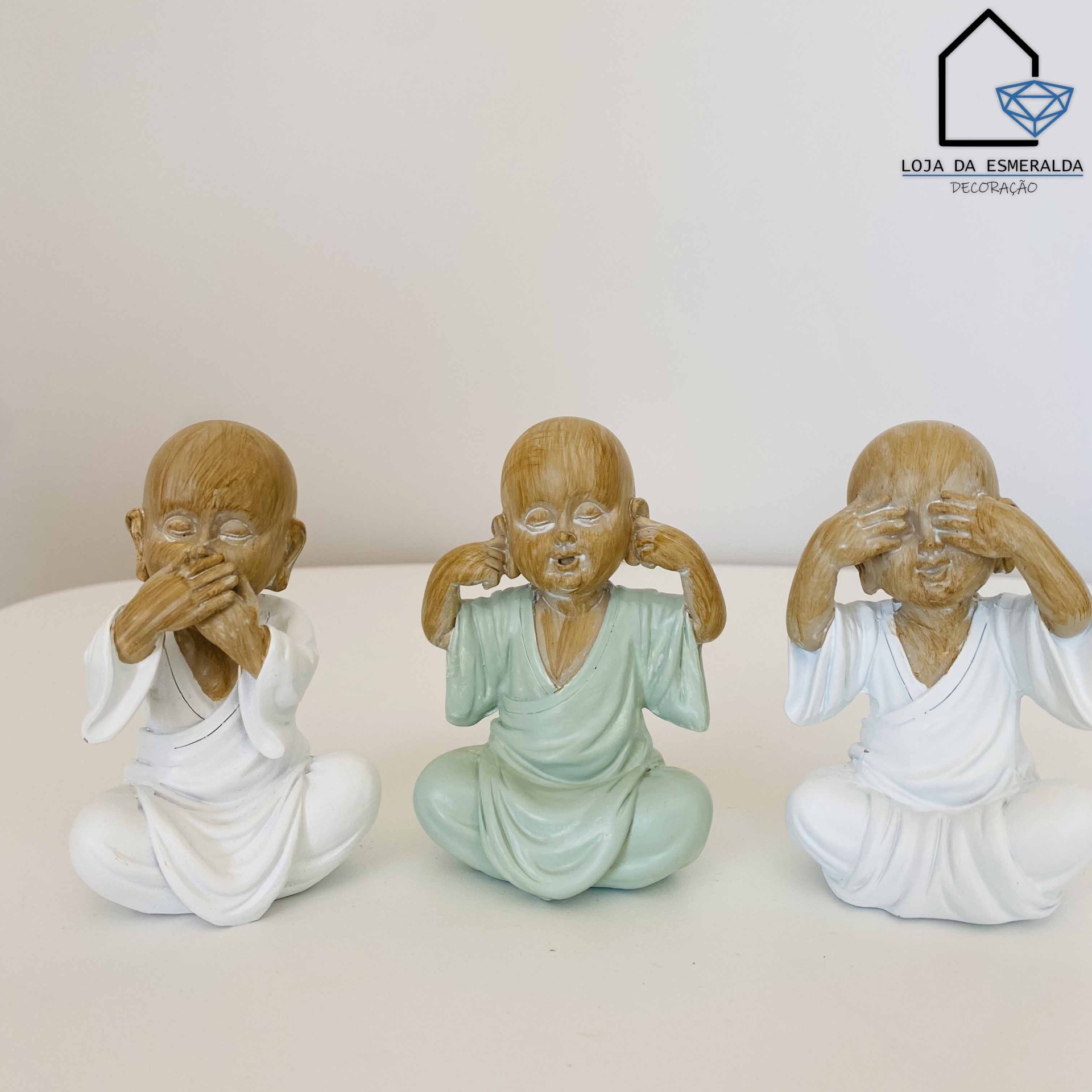 Três estatuetas de monges em cerâmica em poses de não ouvir, não falar, não ver