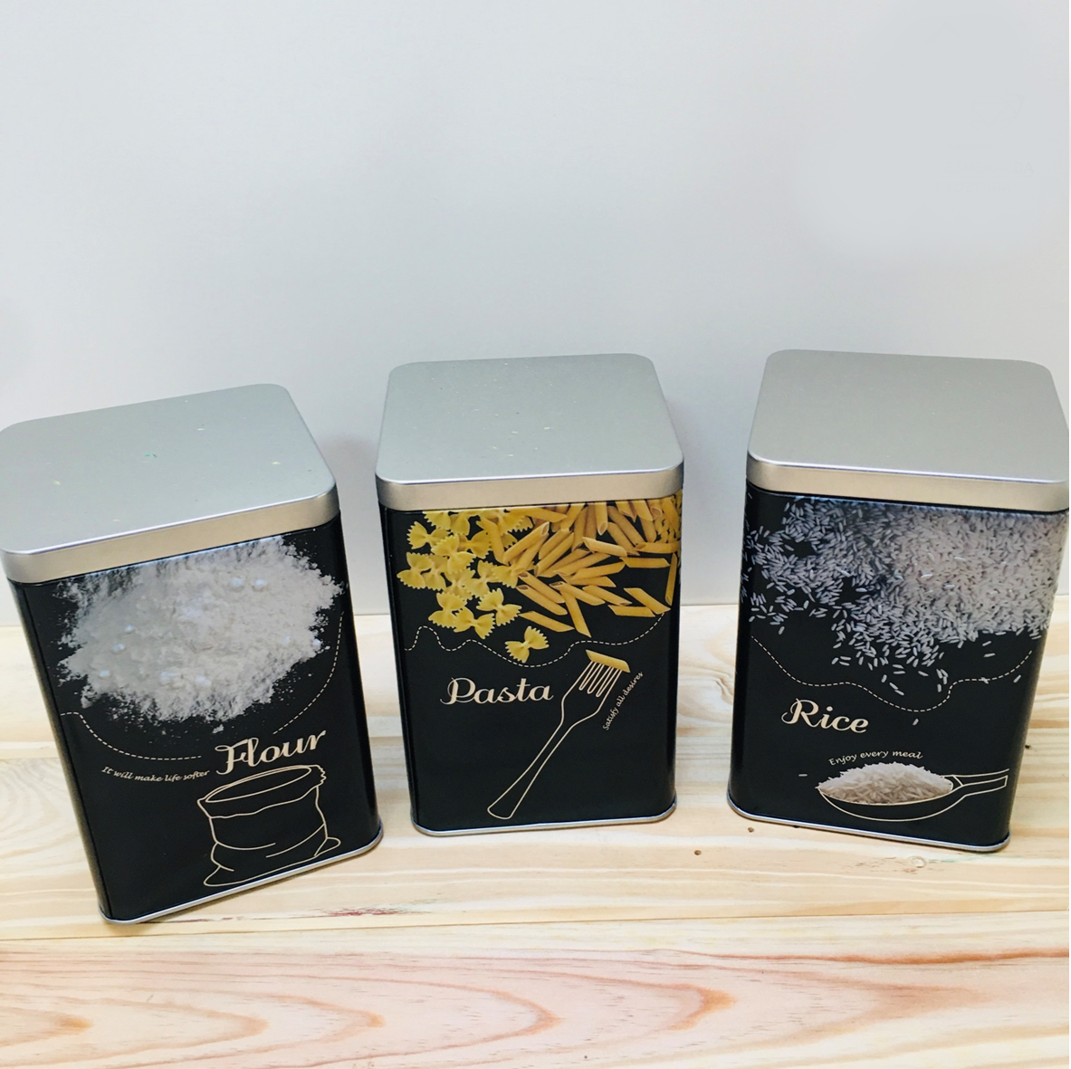 Três latas metálicas para farinha, massa e arroz com design preto e tampa prateada