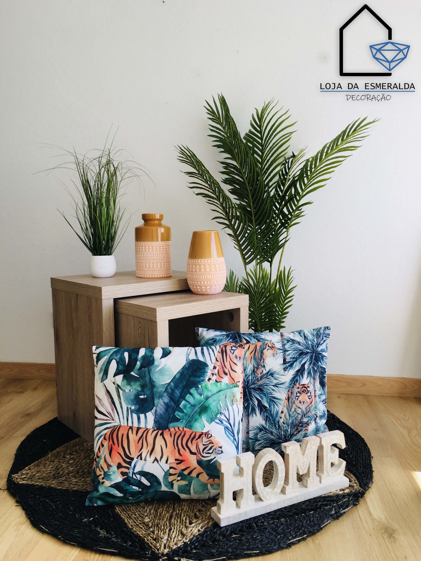 Conjunto decorativo com almofadas estampadas, suporte decorativo HOME, vasos e plantas artificiais sobre mesas de madeira