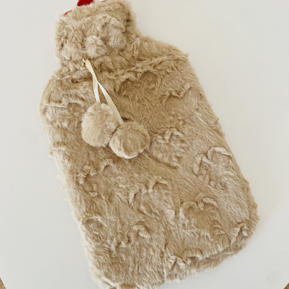 Frasco de água quente com capa peluda bege e pompons.