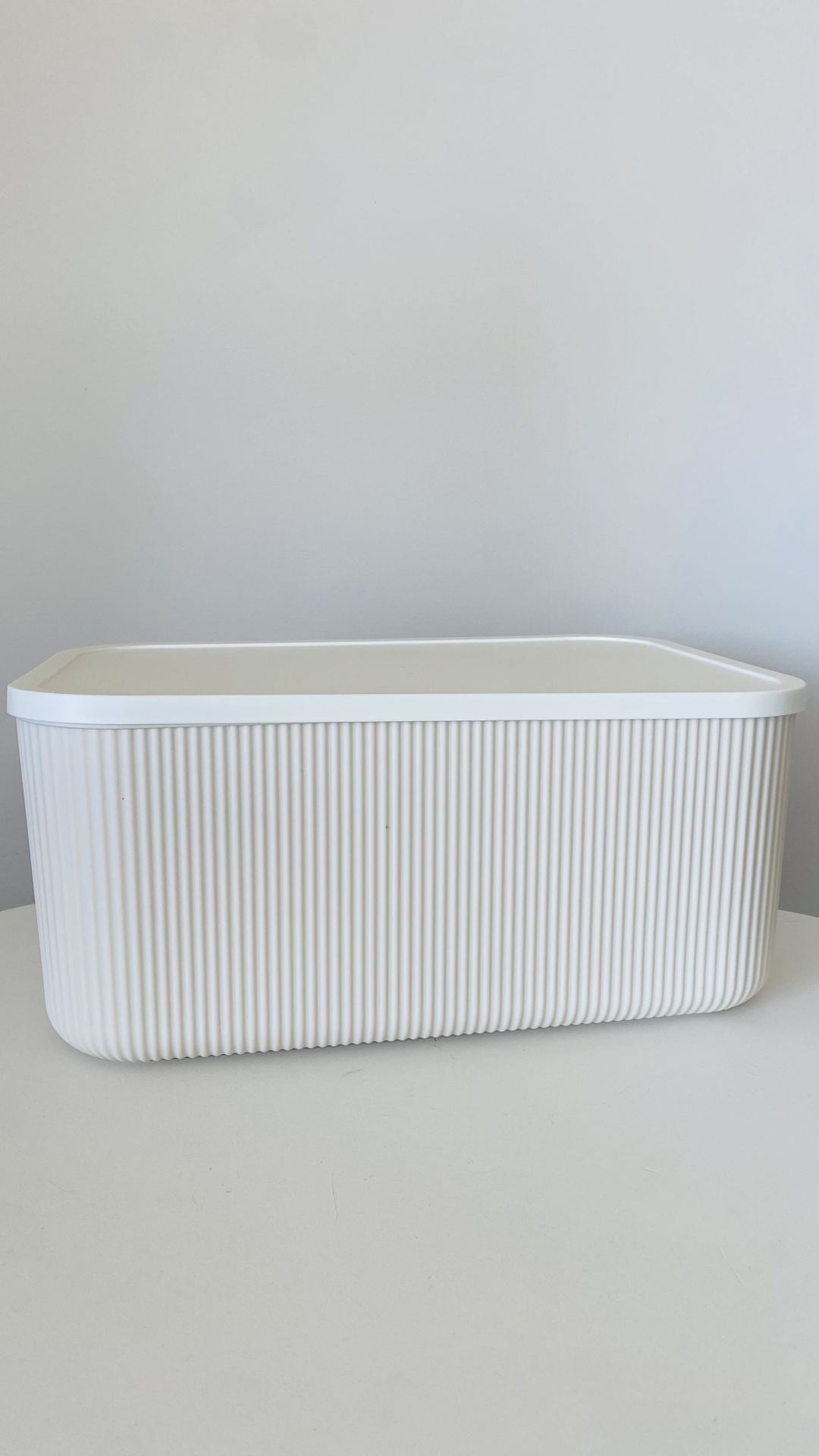 Caixa de armazenamento branca retangular com tampa e textura de ranhuras verticais.