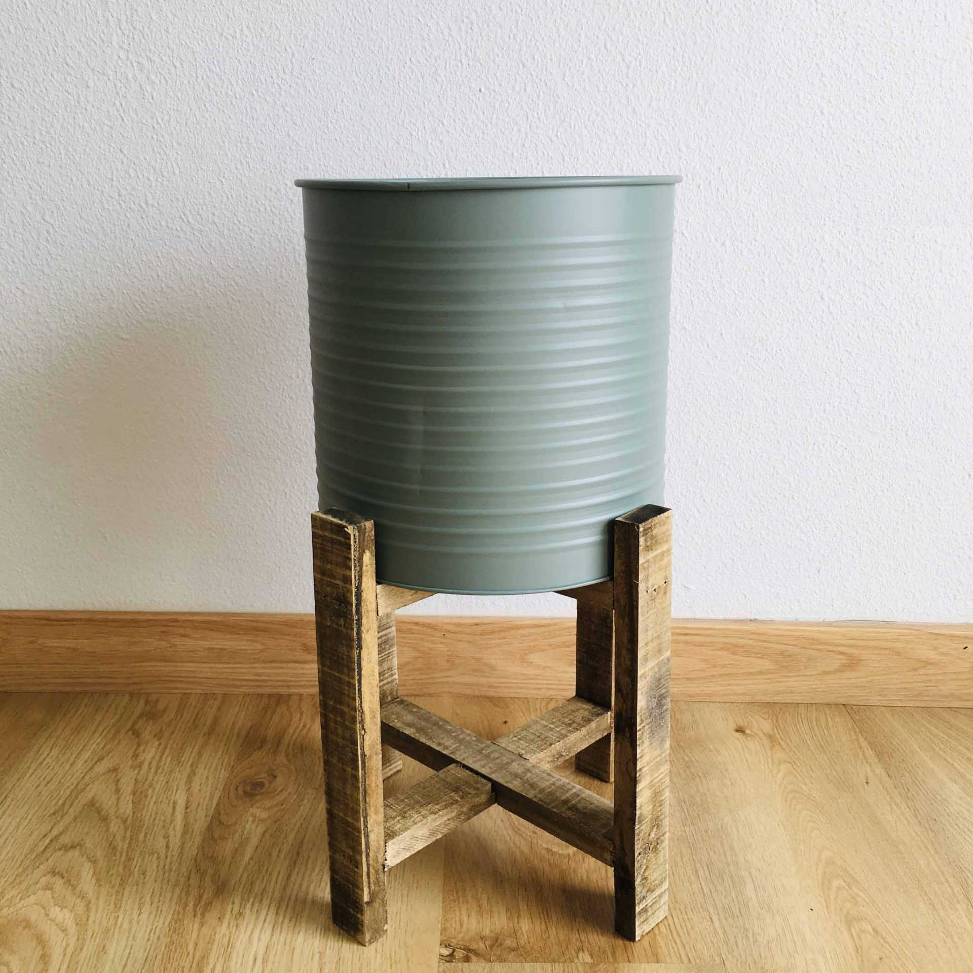 Vaso cinza esverdeado em suporte de madeira sobre chão de madeira