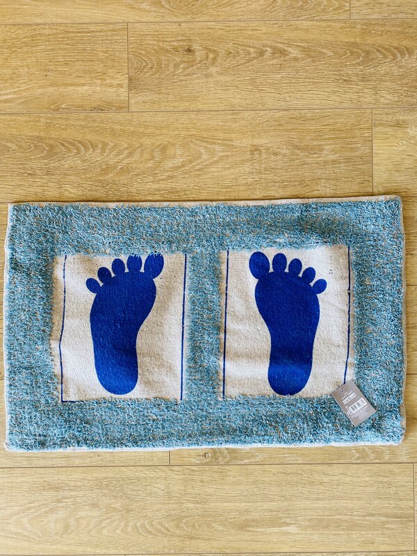 Tapete azul com pegadas azuis sobre chão de madeira