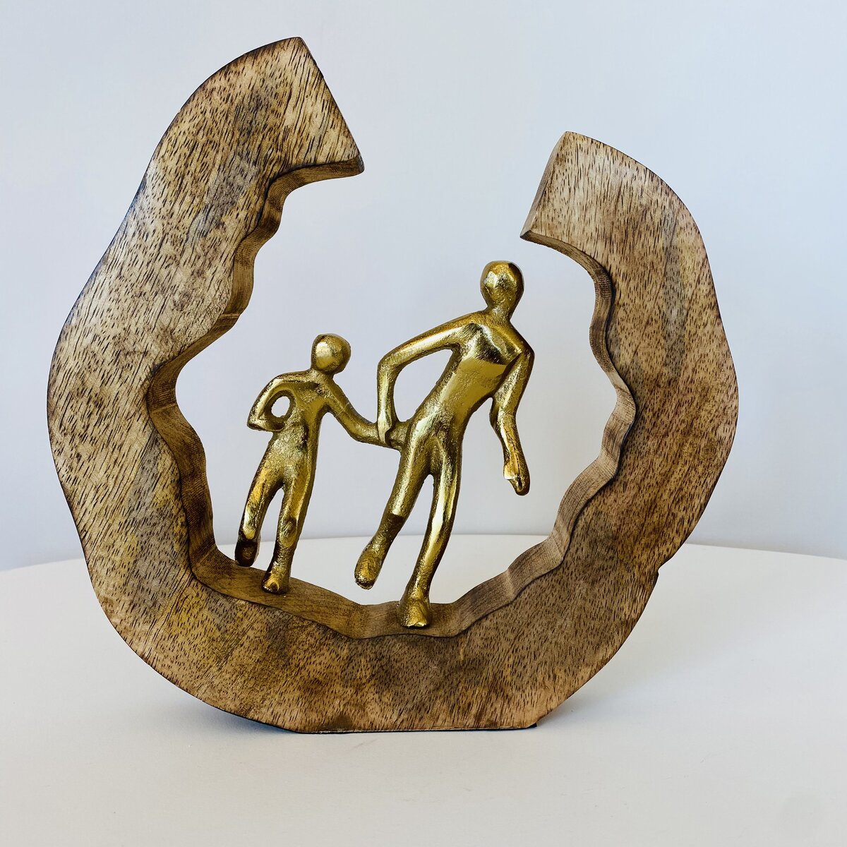 Escultura decorativa de madeira com figuras douradas de pessoas dentro de semi-círculo