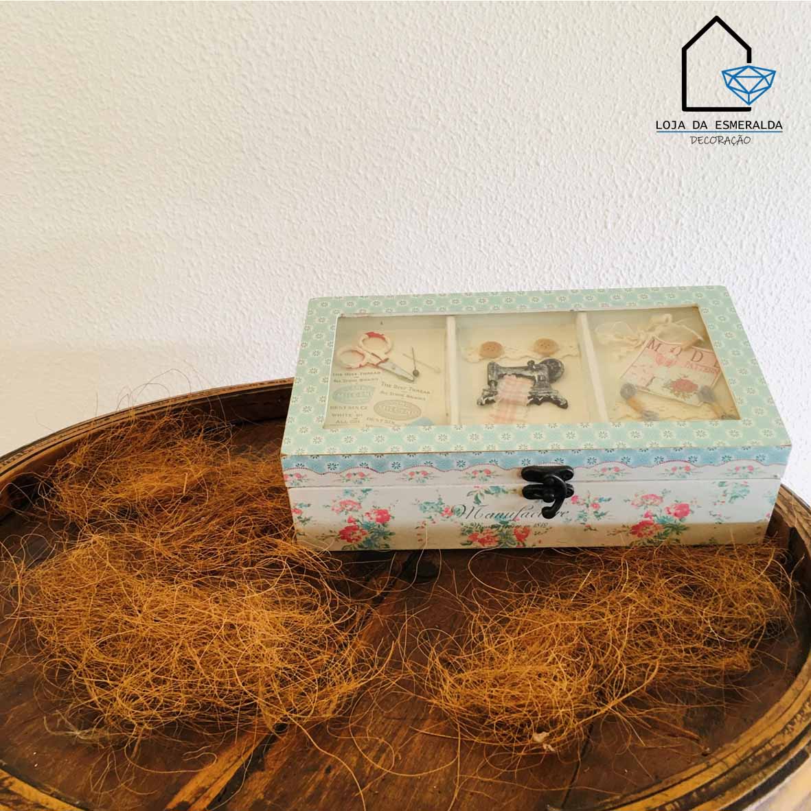 Caixa de madeira decorativa floral com tampa de vidro sobre bandeja de madeira escura com fibras secas