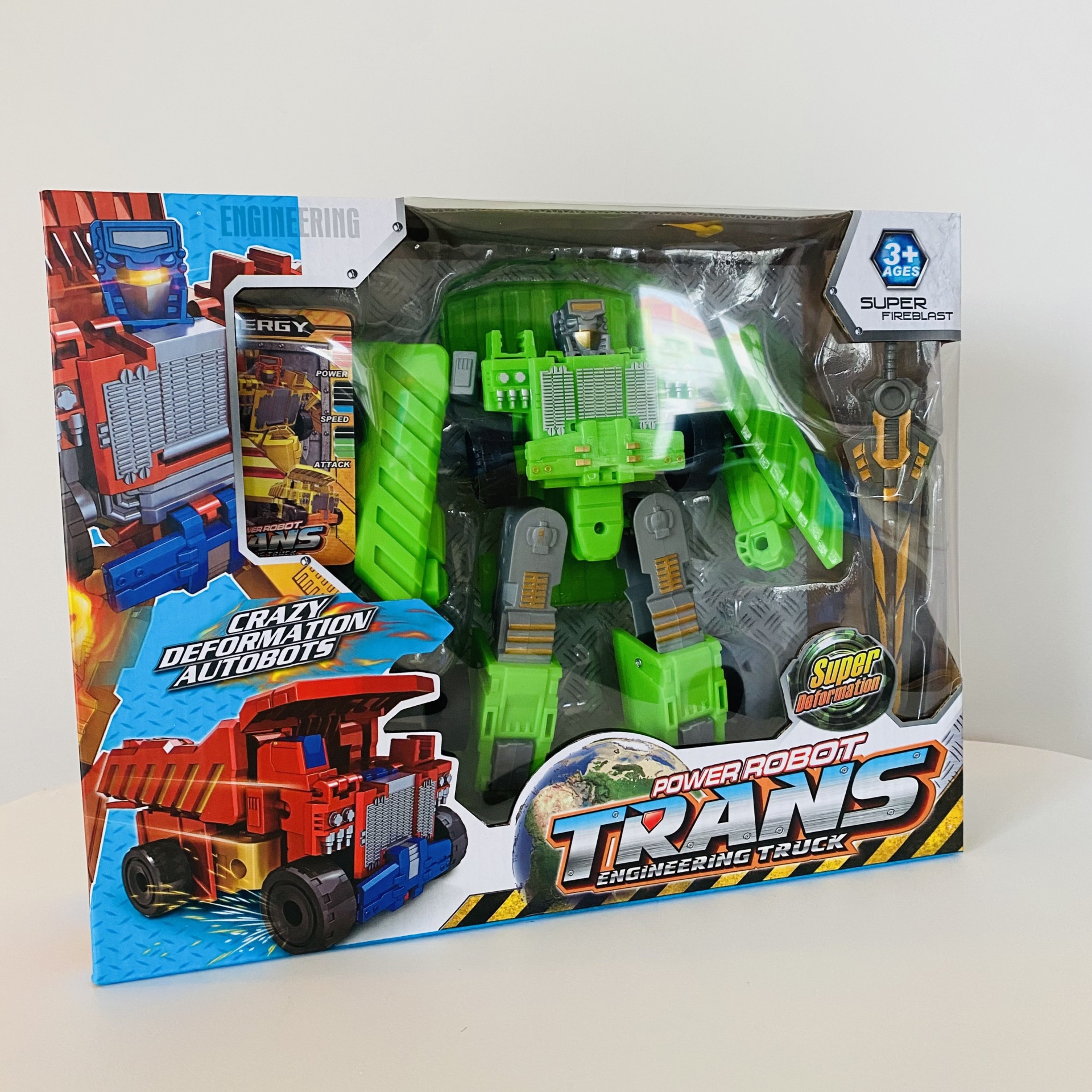 Boneco robô verde em caixa de brinquedo com imagens de camião e texto